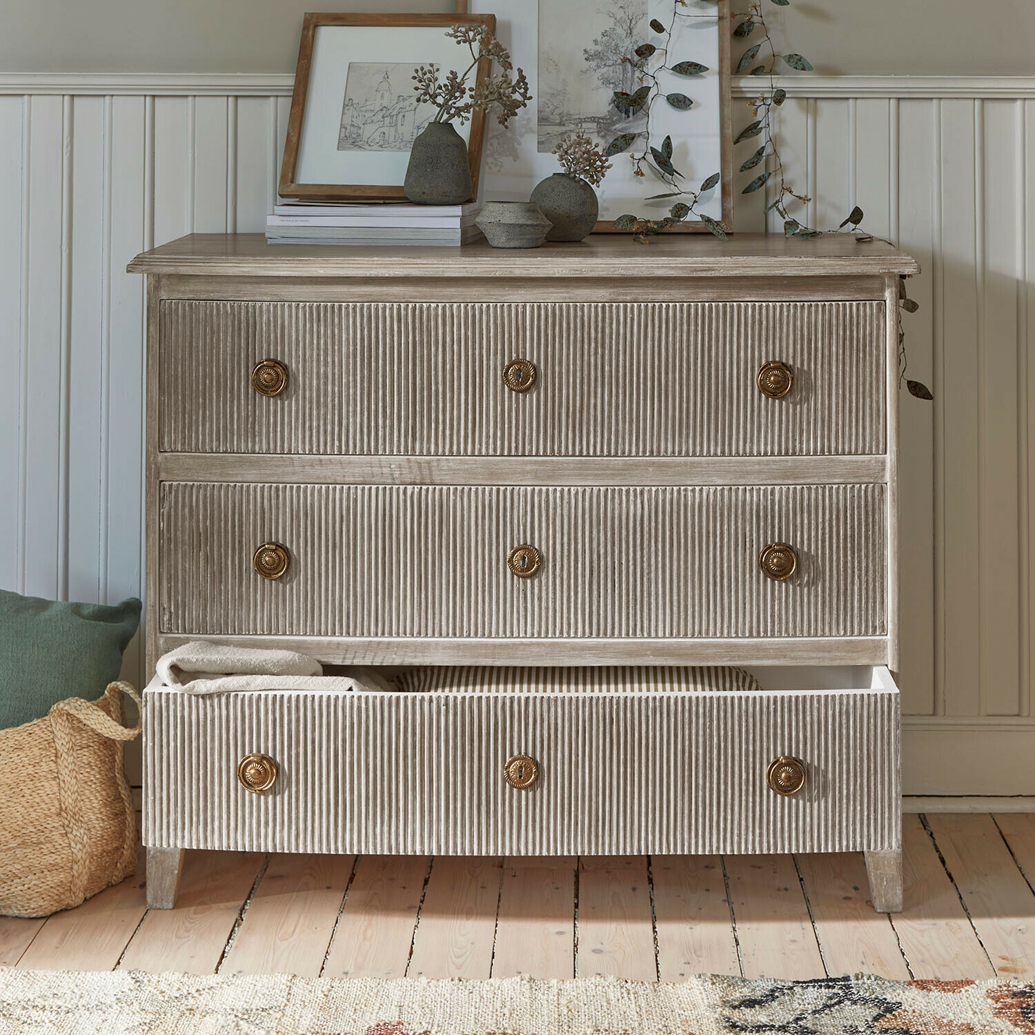 Ladekast van geribbeld hout in beige met messing handgrepen en decoraties bovenop