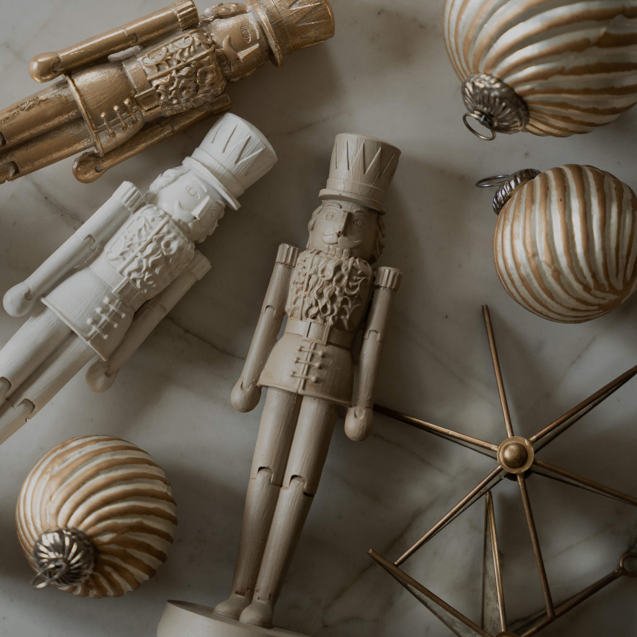 Houten soldaatfiguren en gouden kerstballen op marmeren achtergrond, feestelijke decoratie