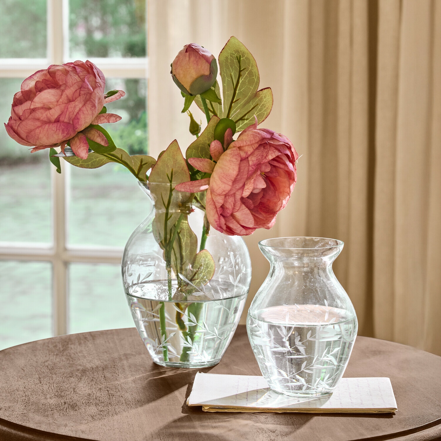 Vaas set van 2 Paimpont Transparante glazen vazen met gegraveerd bladmotief, één met roze bloemen, op een houten tafel