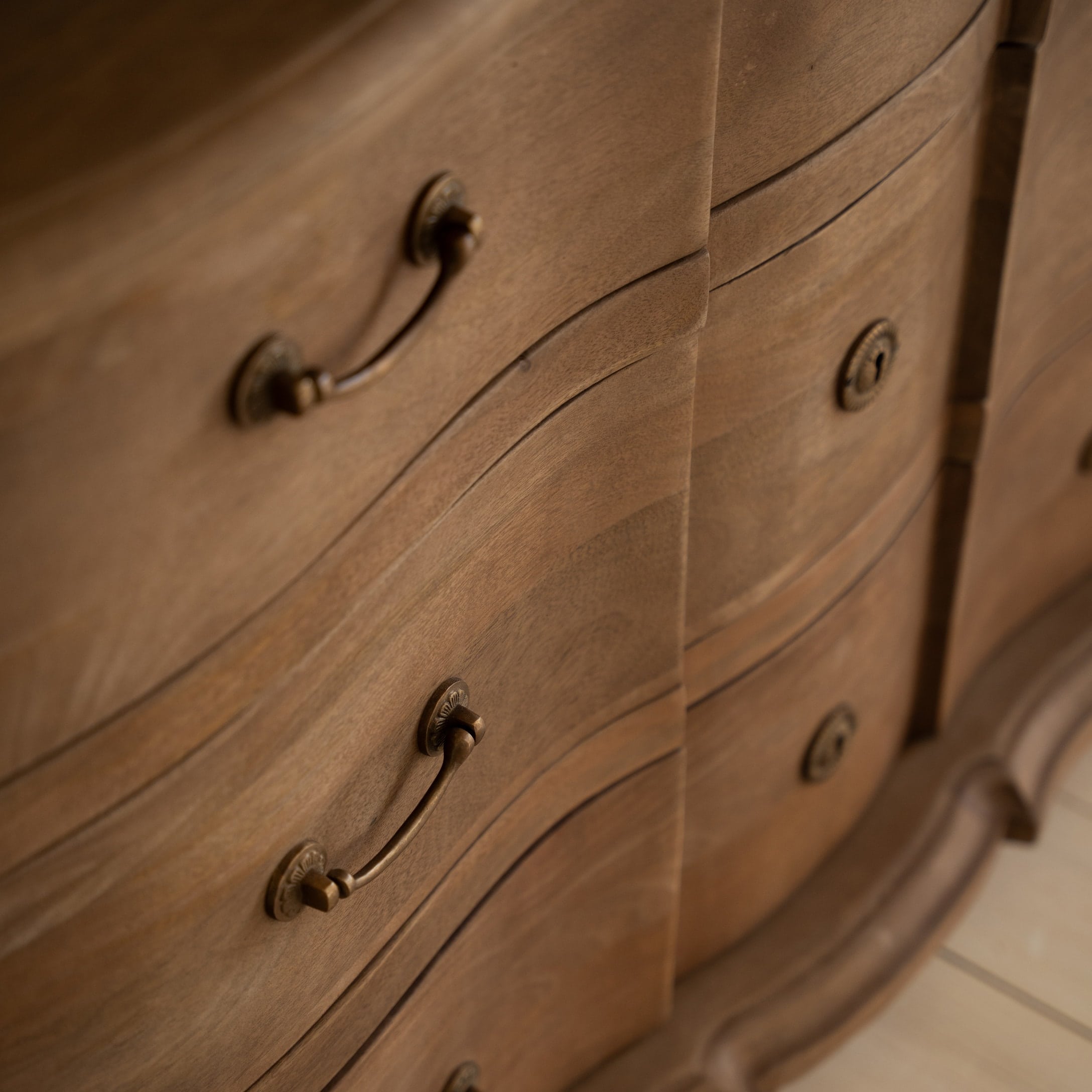 Close-up van een houten ladekast met decoratieve messinggrepen en natuurlijke houtafwerking