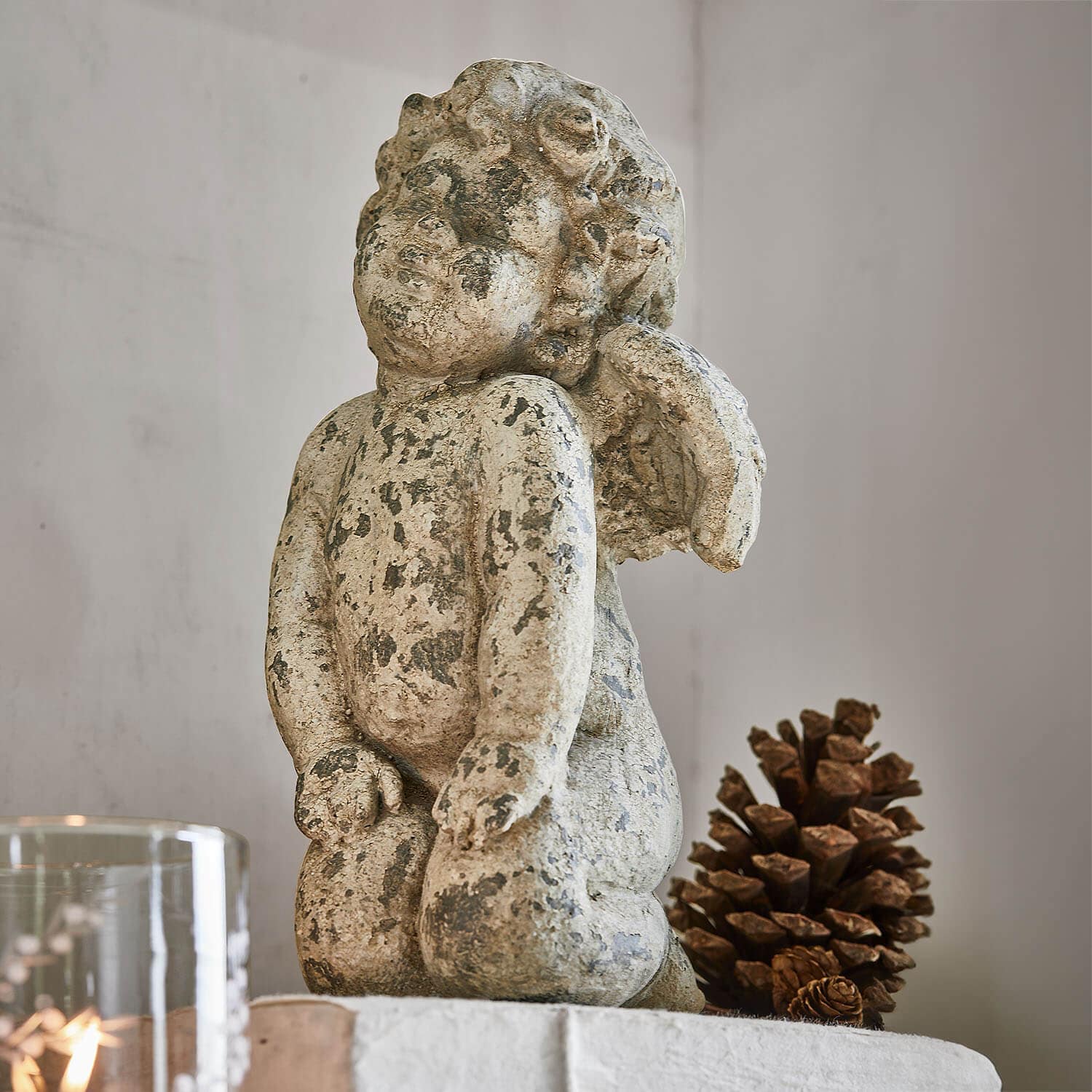 Beeldje van engel van verouderd beige steen, interieurdecoratie met natuurlijke dennenappel
