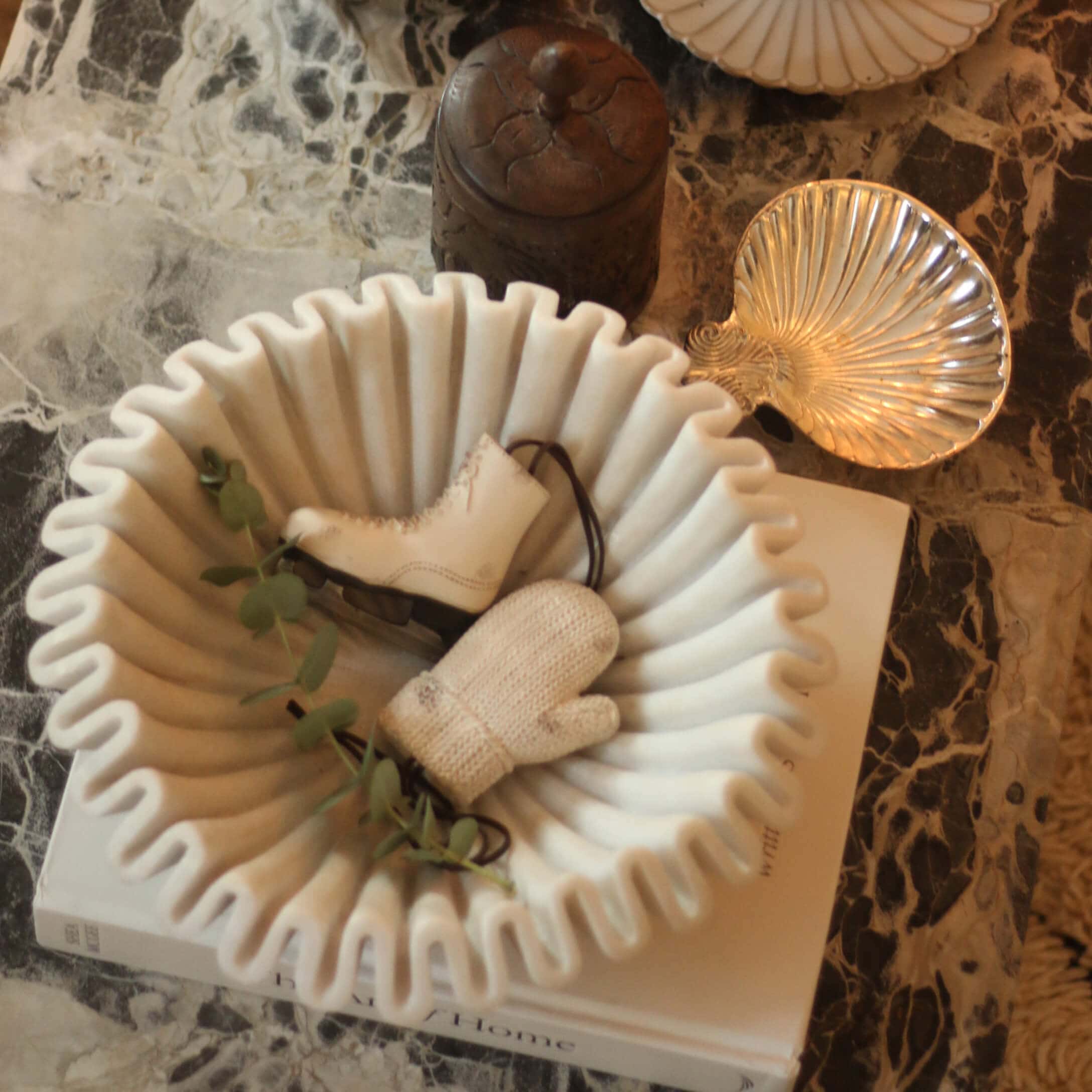 Witte keramische schaal met golvende rand, versierd met schaats en want op marmeren tafel