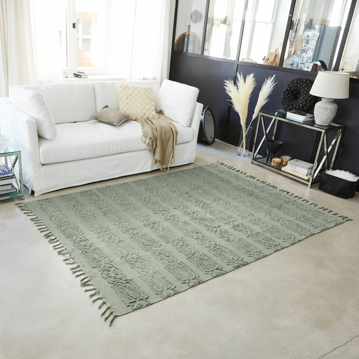Groen decoratief vloerkleed met franjes op lichte vloer in moderne woonkamer
