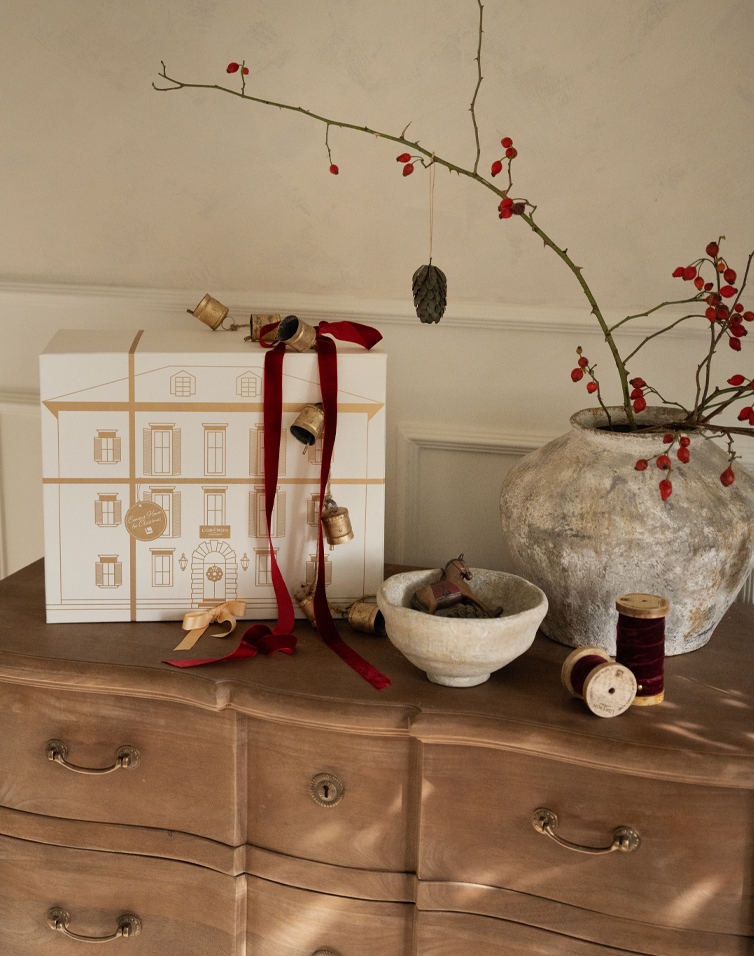 Kerstdecoratie met witte doos, rode linten en keramische vaas met tak en rode bessen