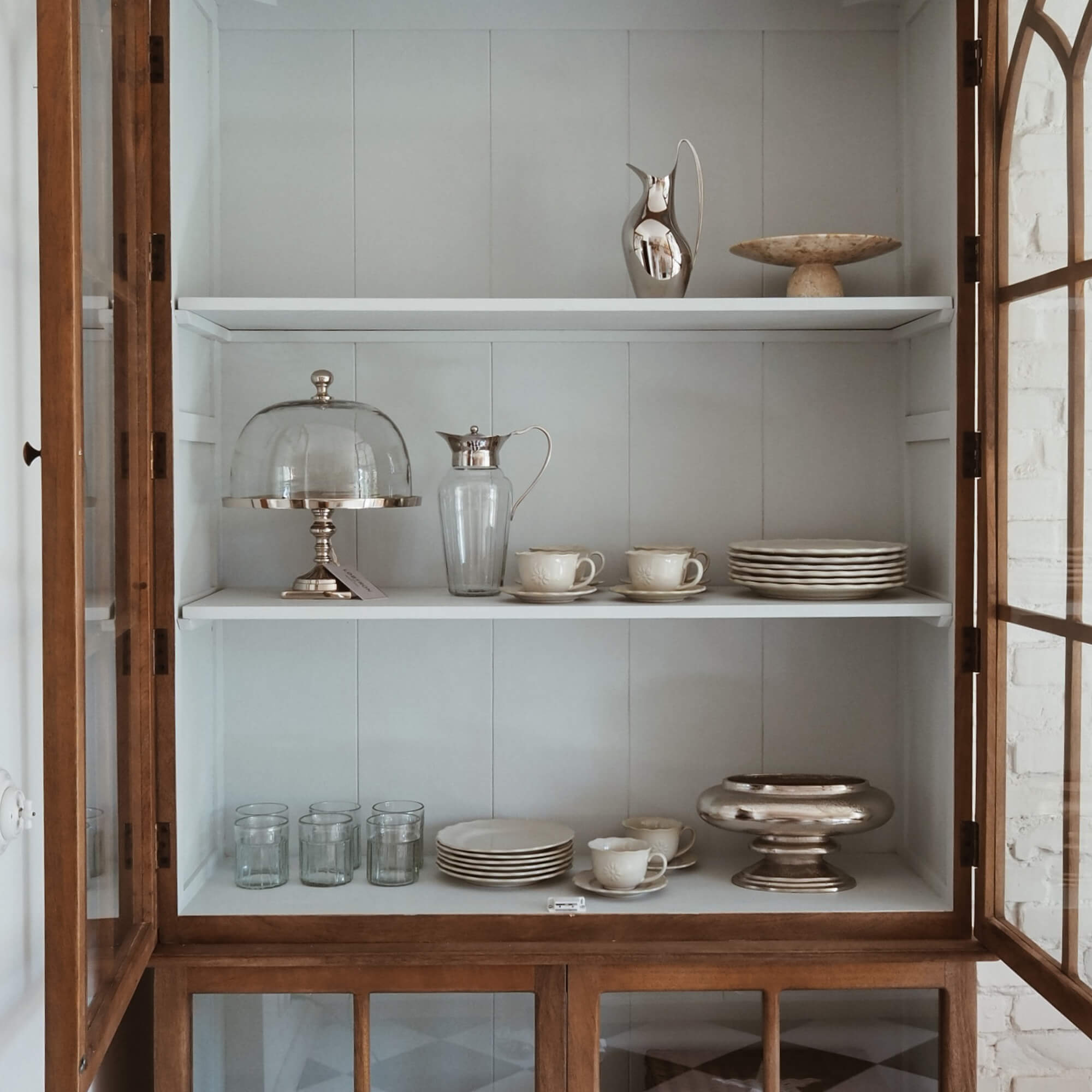 Houten vitrinekast met witte planken, porseleinen servies en glazen voor thuis