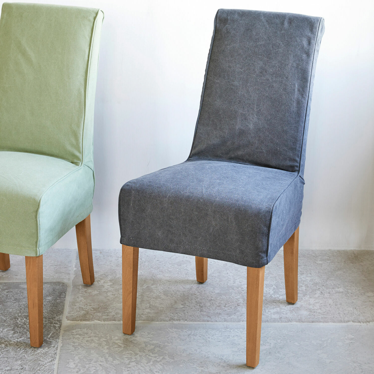 Grijze gestoffeerde stoel met lichte houten poten op lichte vloer, eetkamermeubel