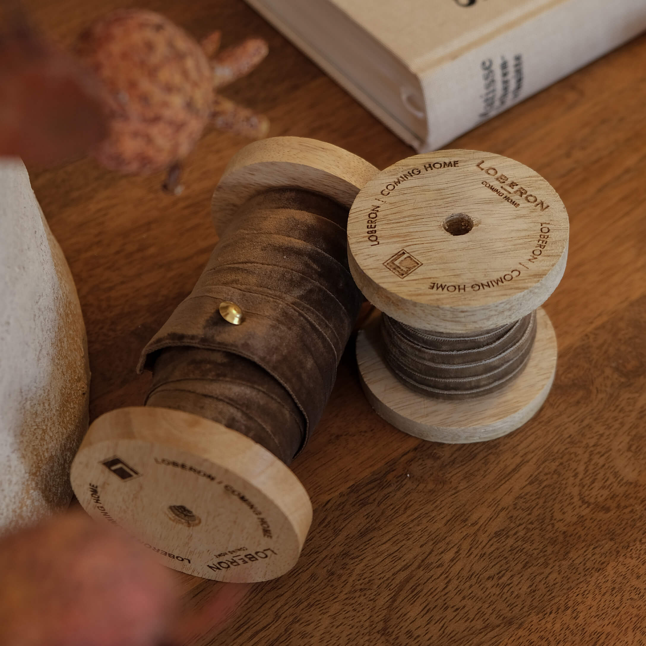 Houten spoelen met bruine fluwelen lint op houten tafel, sfeervolle interieurdecoratie