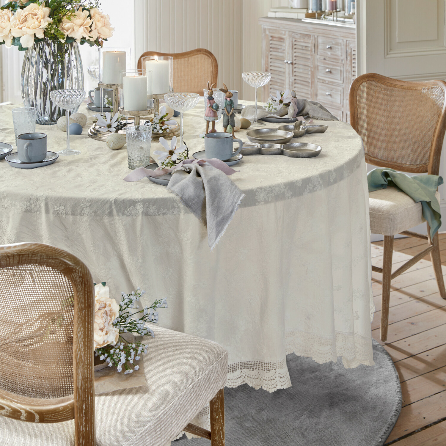 Elegante tafel met crèmekleurig kanten tafelkleed, paasdecoratie en grijs servies