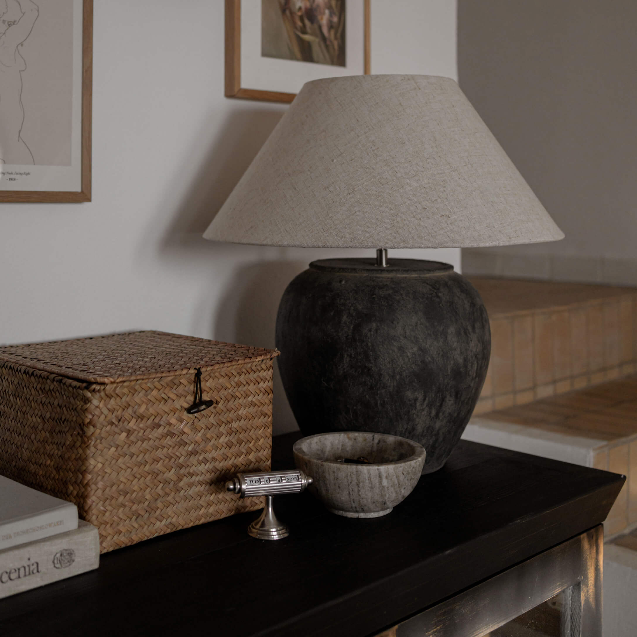 Tafellamp met zwarte keramische voet en beige kap op een donkere tafel in de woonkamer