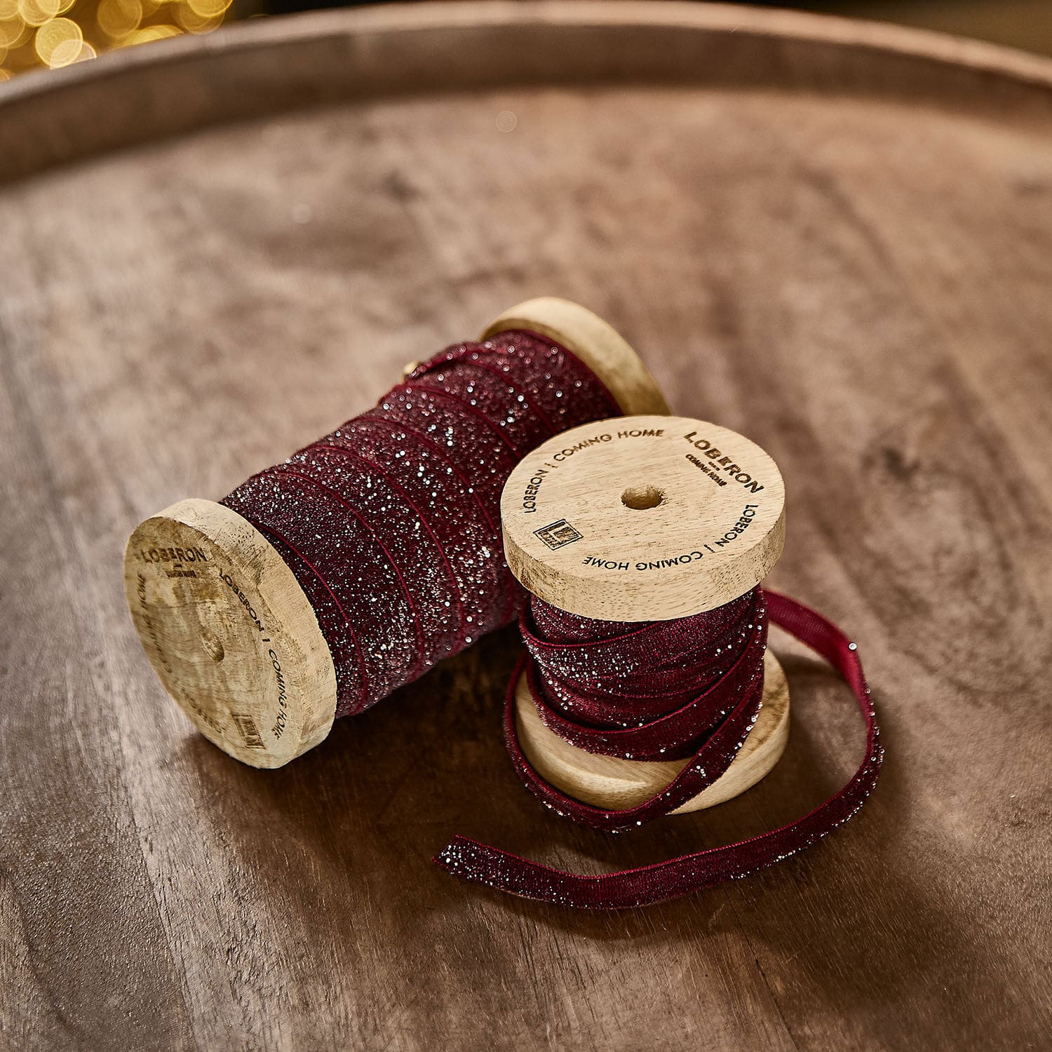 Fluwelen lint set van 2 Risorio Bordeaux glinsterlint op houten spoelen op houten tafel voor decoratie en knutselen