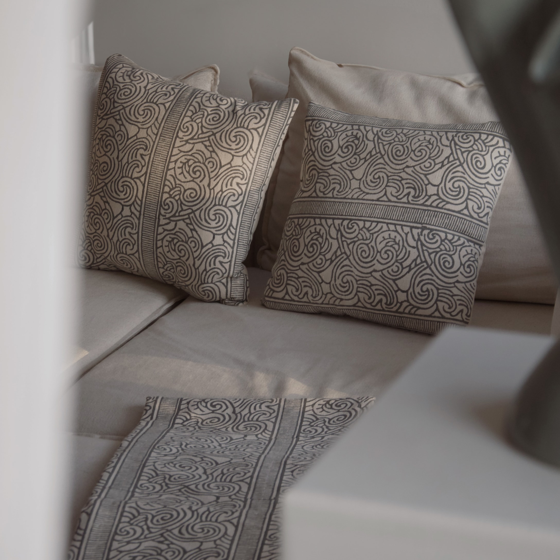 Beige kussens en tafelloper met zwart patroon op lichte bank voor interieurdecoratie