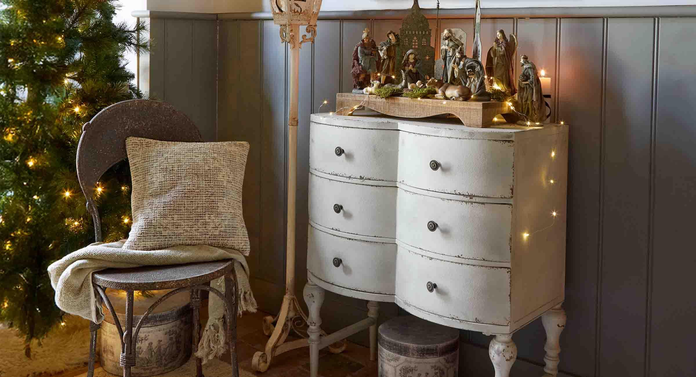 Witte antiek ogende ladekast met houten kerststal en feestelijke decoratie in een gezellige kamer