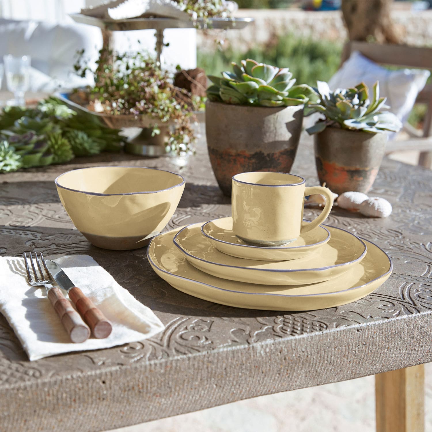 Set keramisch servies in crème met blauwe rand op rustieke tafel met vetplanten decoratie