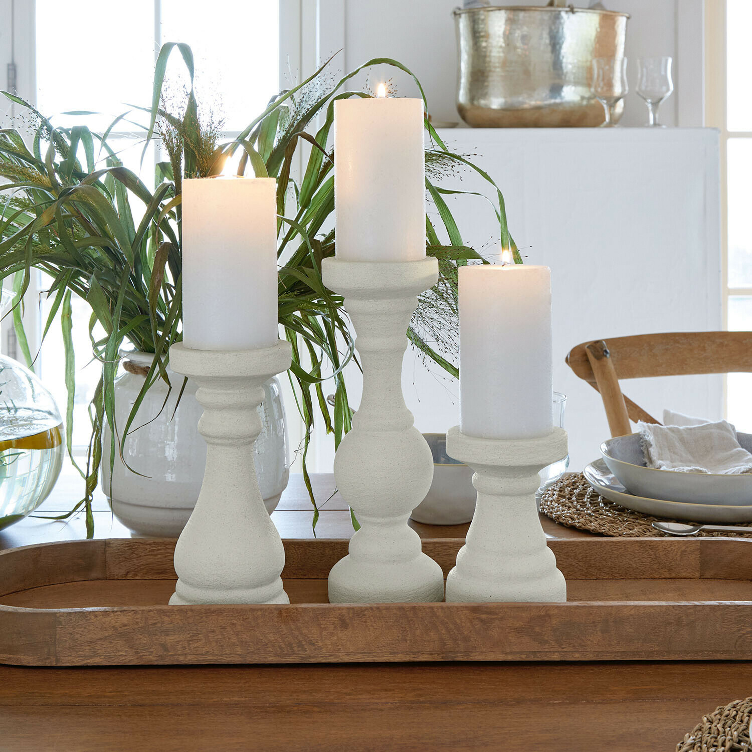 Set van drie witte stenen kandelaars op een houten dienblad als tafeldecoratie