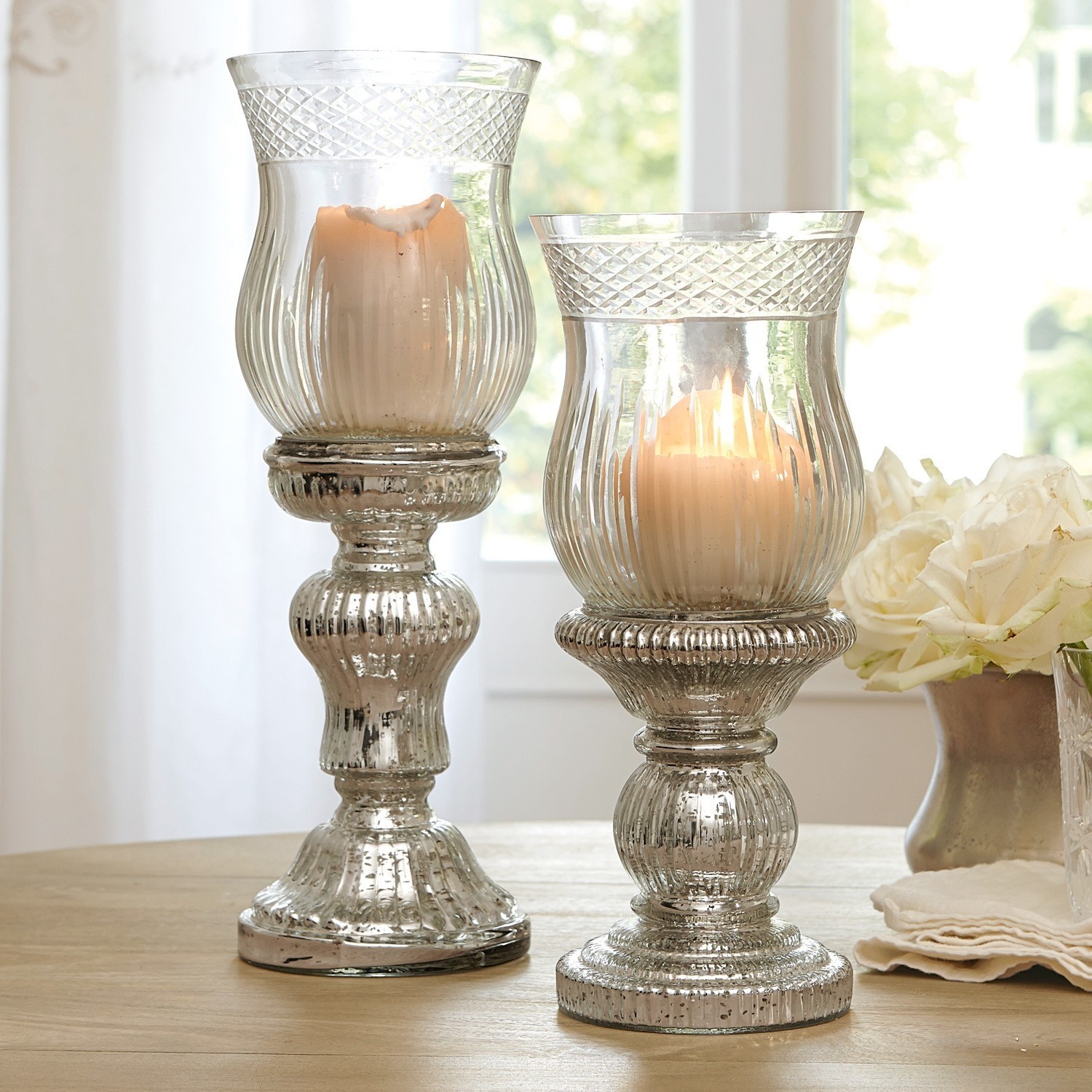 Kandelaar set van 2 Luisant Twee decoratieve glazen kandelaars met antiek zilveren effect op houten tafel in lichte kamer