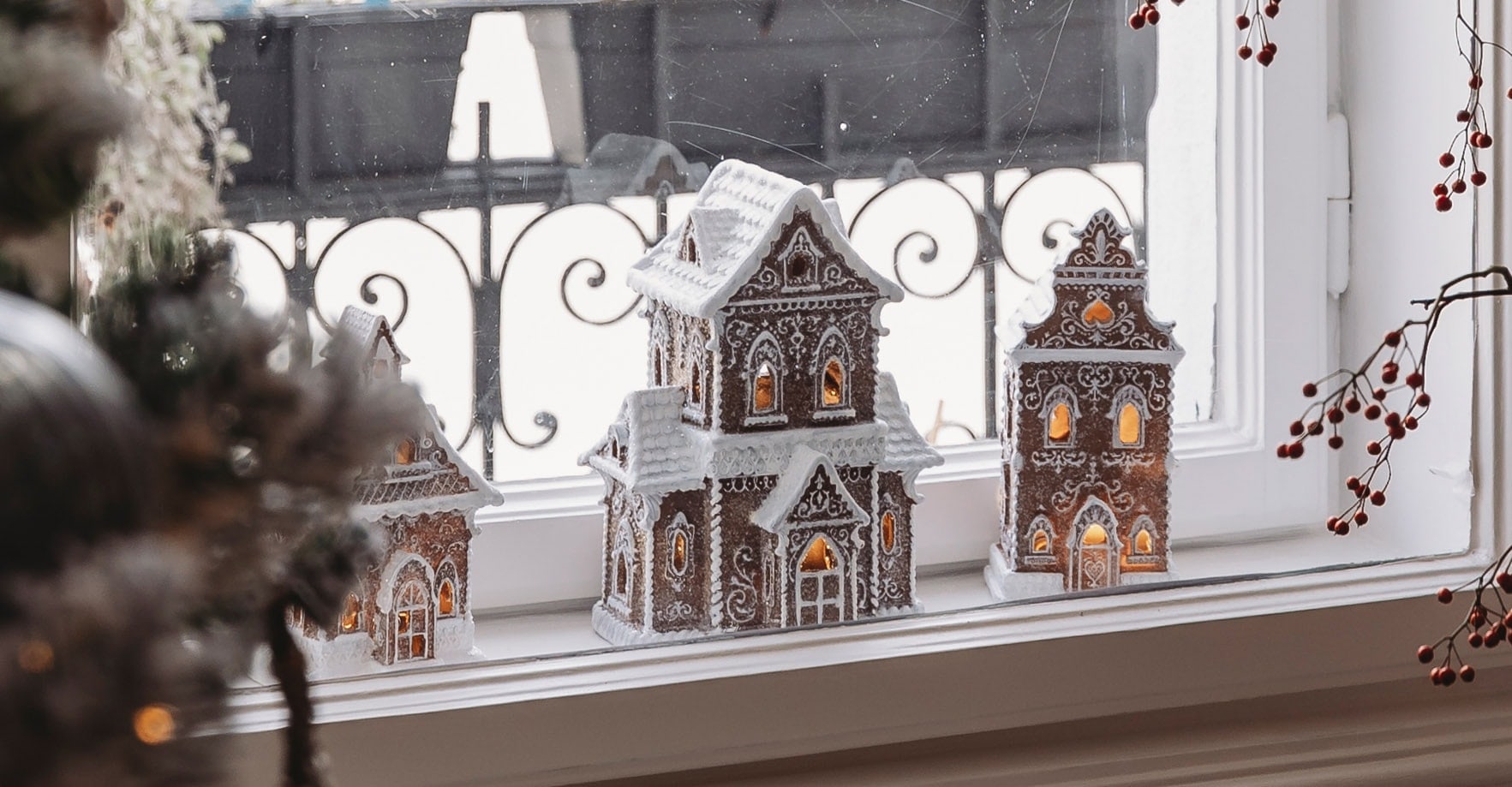 Decoratieve peperkoekhuisjes met witte glazuur en verlichting op de vensterbank voor Kerstmis