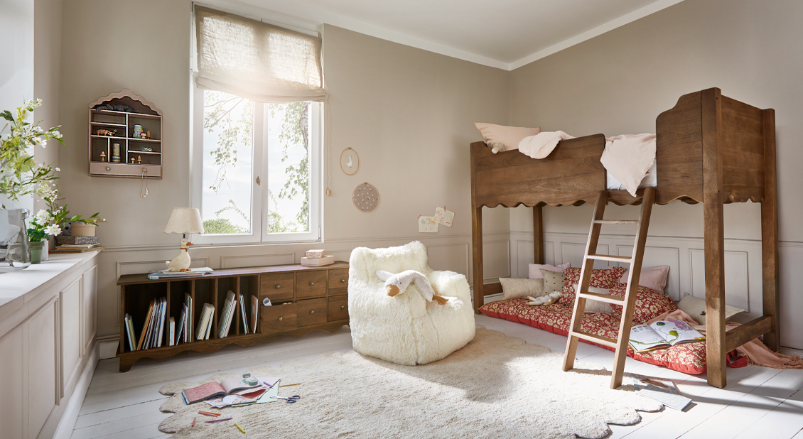 Houten hoogslaper in natuurlijke kleur met zacht tapijt en witte stoel in lichte kinderkamer
