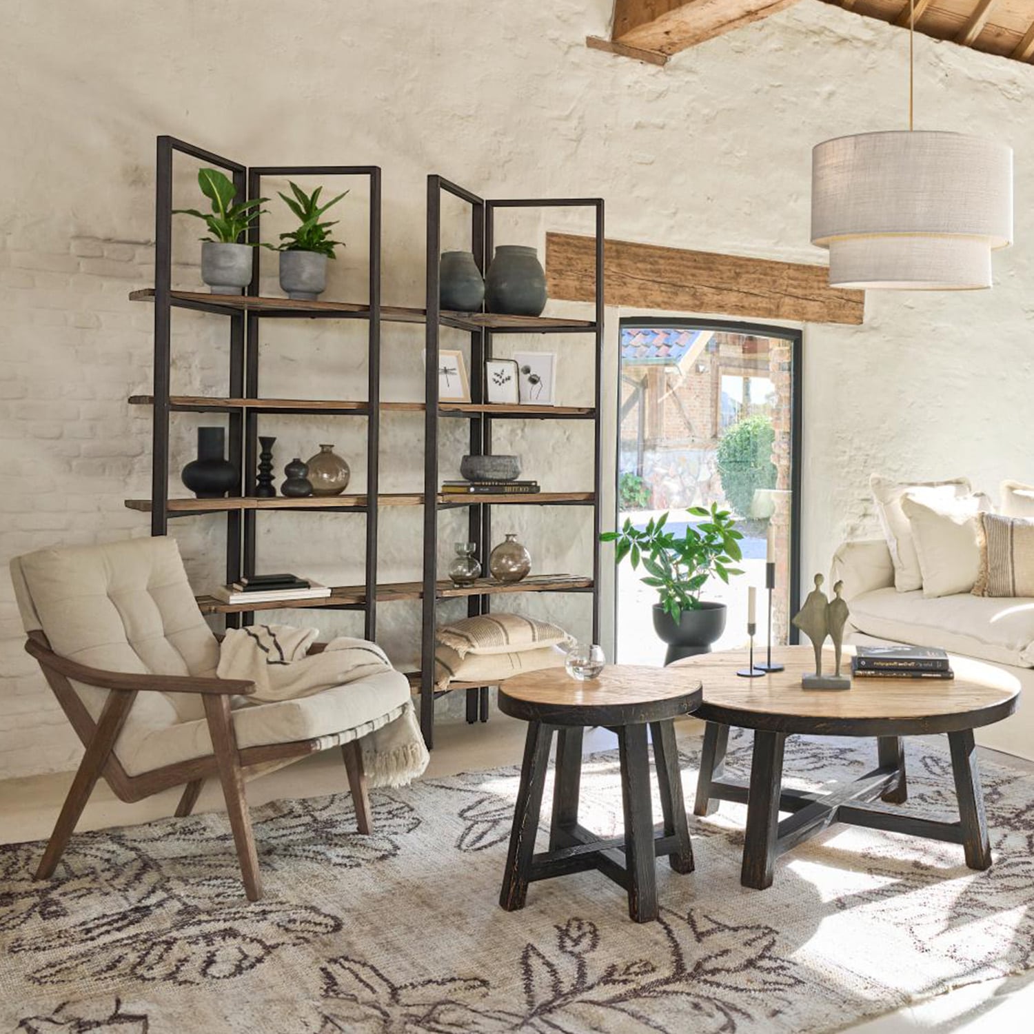 Gezellige woonkamer met houten fauteuil, metalen houten kast en ronde salontafels op een patroon vloerkleed