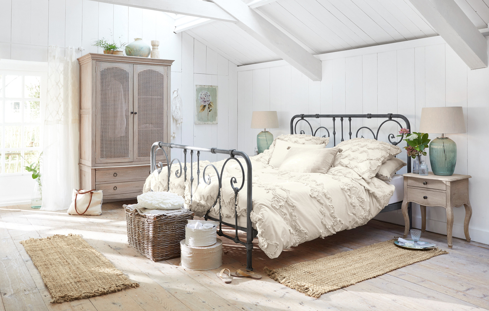 Slaapkamer in shabby chic stijl met zwart metalen bed en crème katoenen beddengoed, natuurlijke accessoires