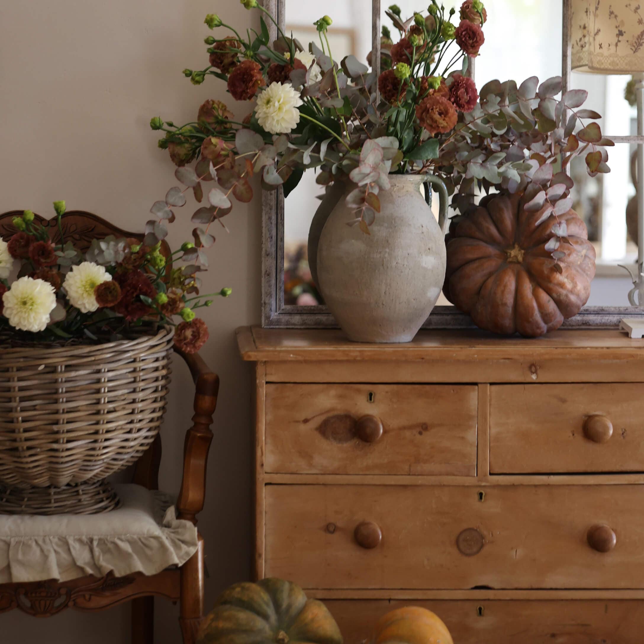 Rustieke houten ladekast met aardewerken vaas, herfstboeket en decoratieve pompoenen in warme setting