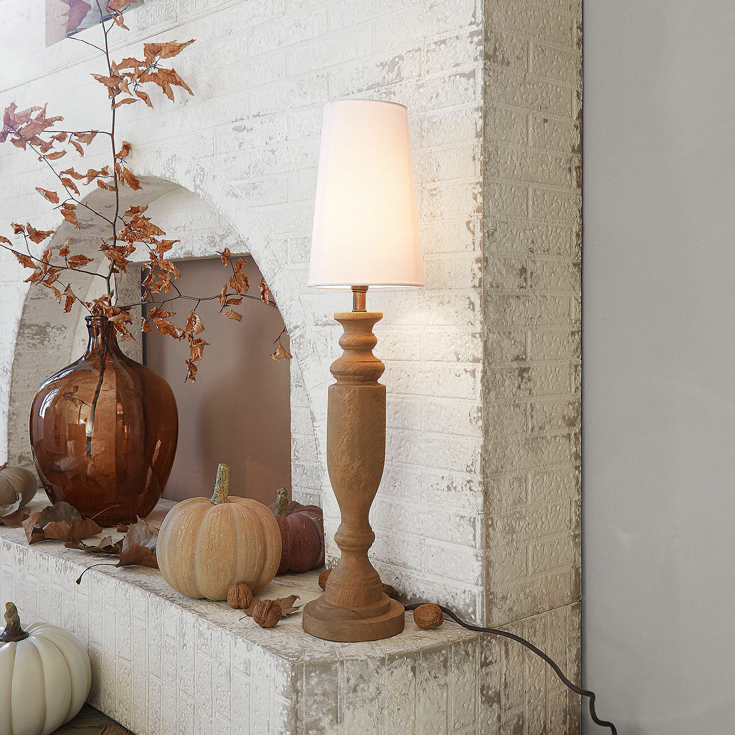 Houten tafellamp met witte kap voor witte bakstenen muur en herfstdecoratie