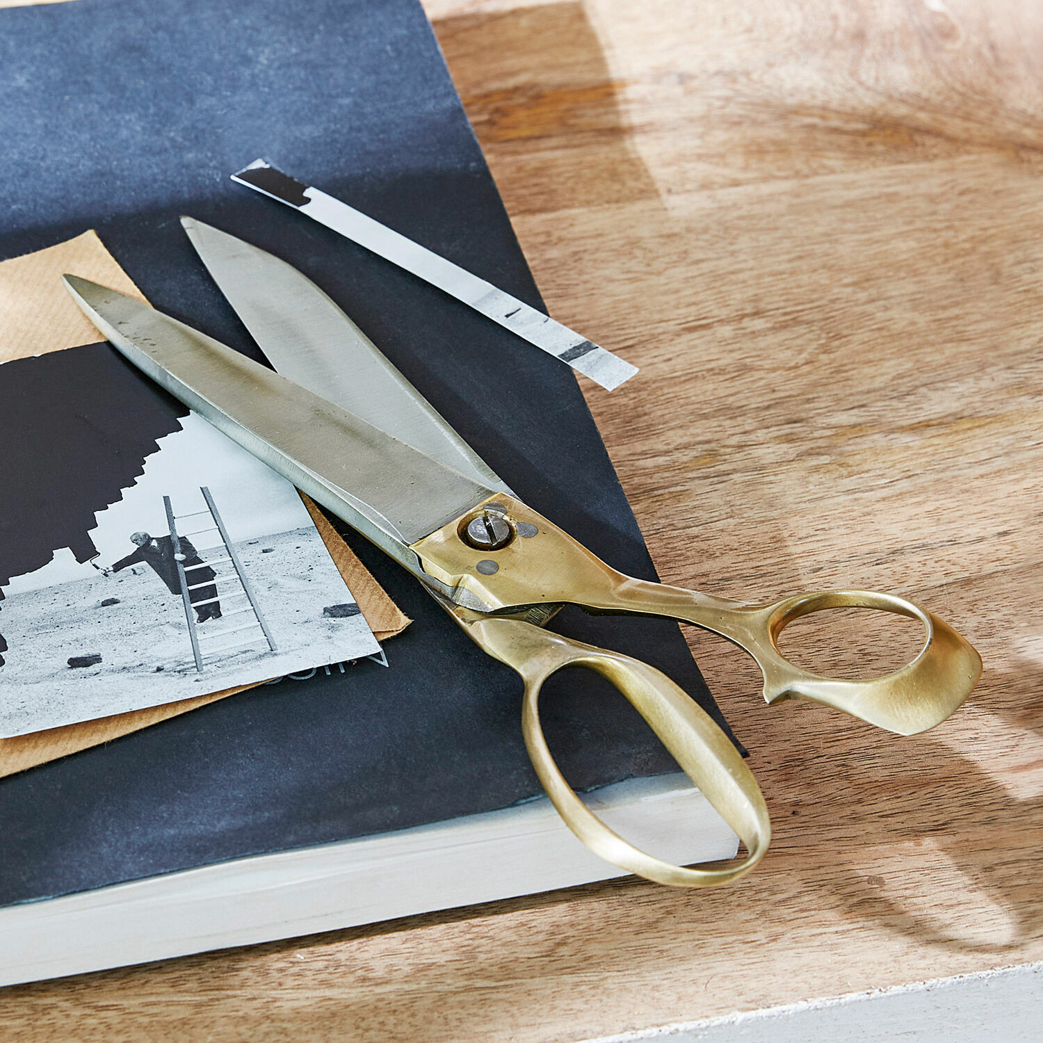 Grote kleermakersschaar van staal en messing op houten tafel met zwart-wit foto