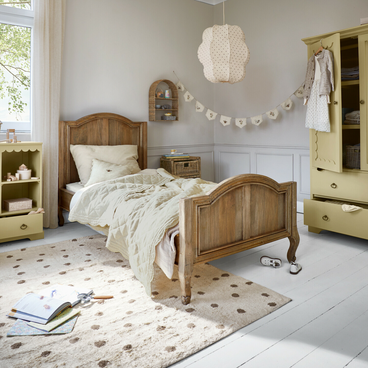 Houten kinderbed met beige beddengoed en crèmekleurig tapijt in lichte kinderkamer