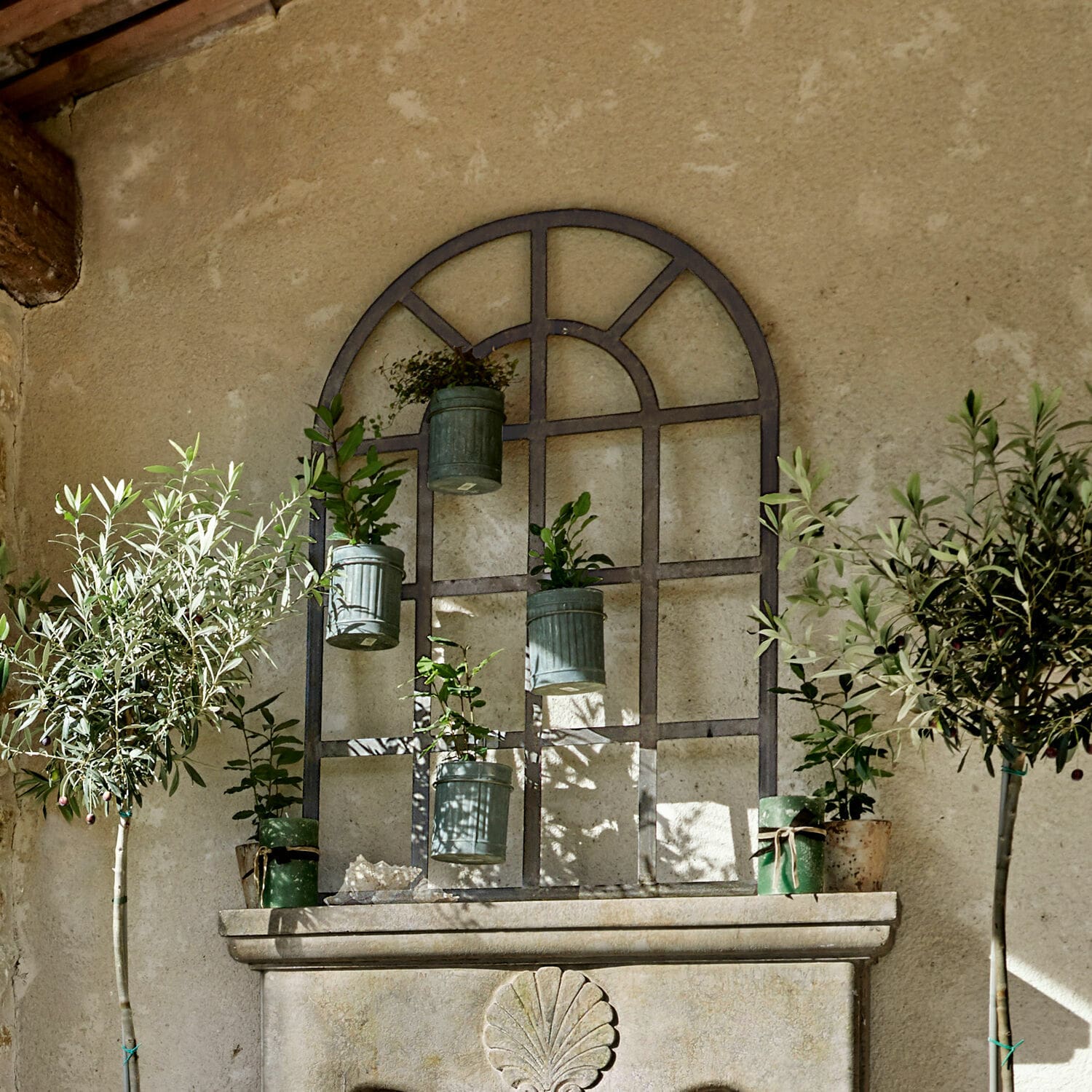 Plantenrek Villandor Metalen wanddecoratie met hangende groene bloempotten en planten tegen een beige muur