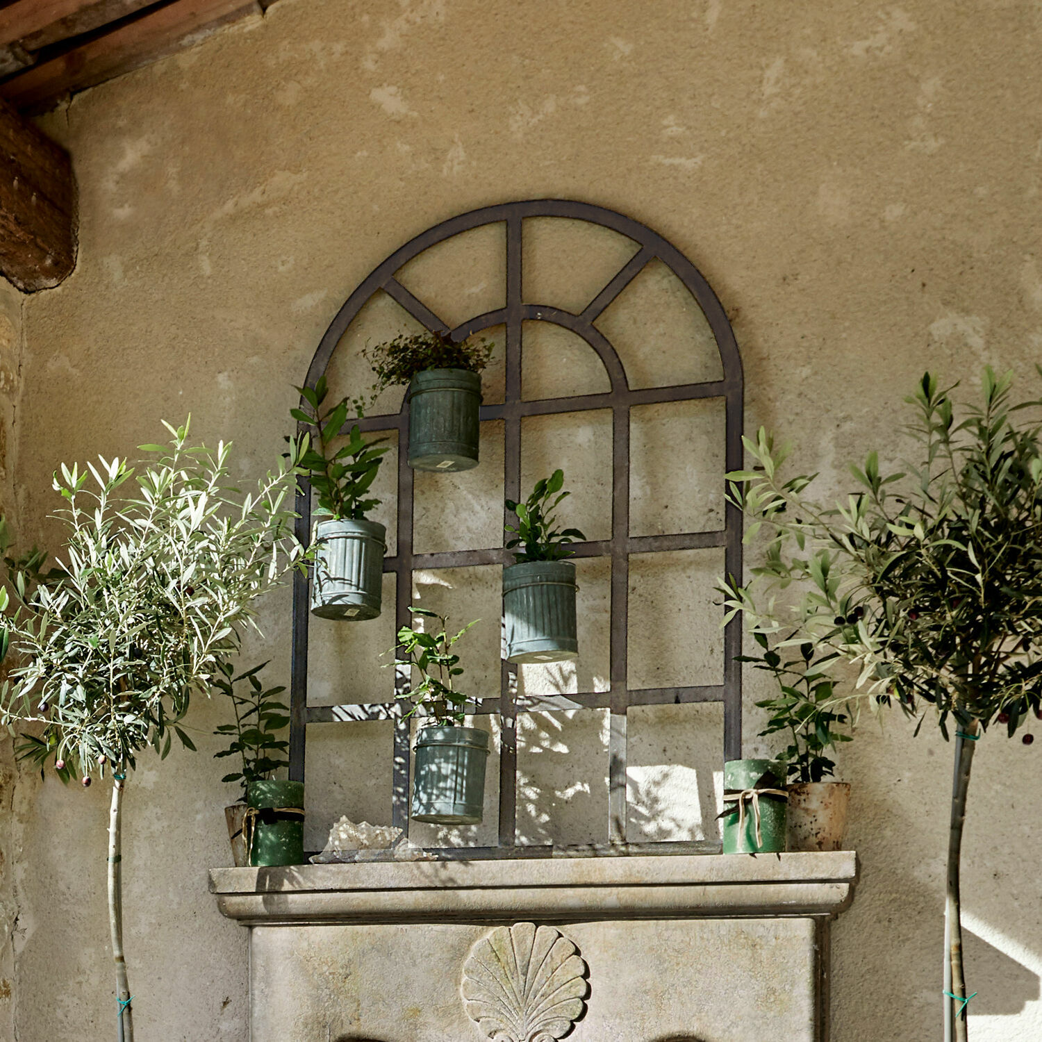Plantenrek Villandor Metalen wanddecoratie met hangende groene bloempotten en planten tegen een beige muur