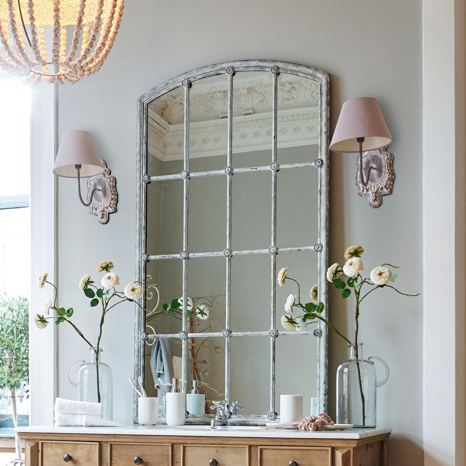 Spiegel Tobiah Grote vintage spiegel met metalen lijst boven houten ladekast met bloemen en wandlampen