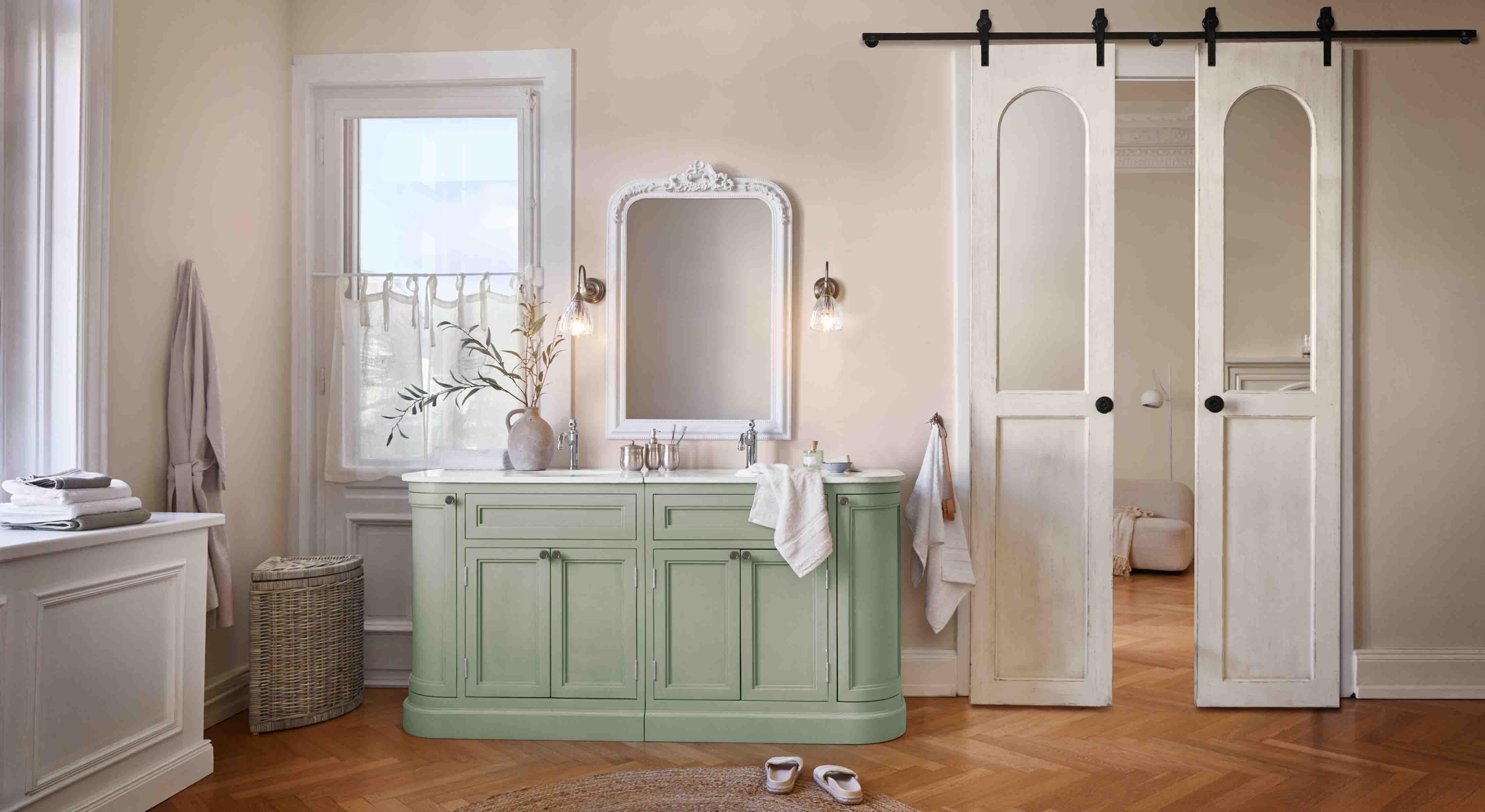 Groene badkamerkast met wit marmeren blad en decoratieve vintage spiegel aan de muur