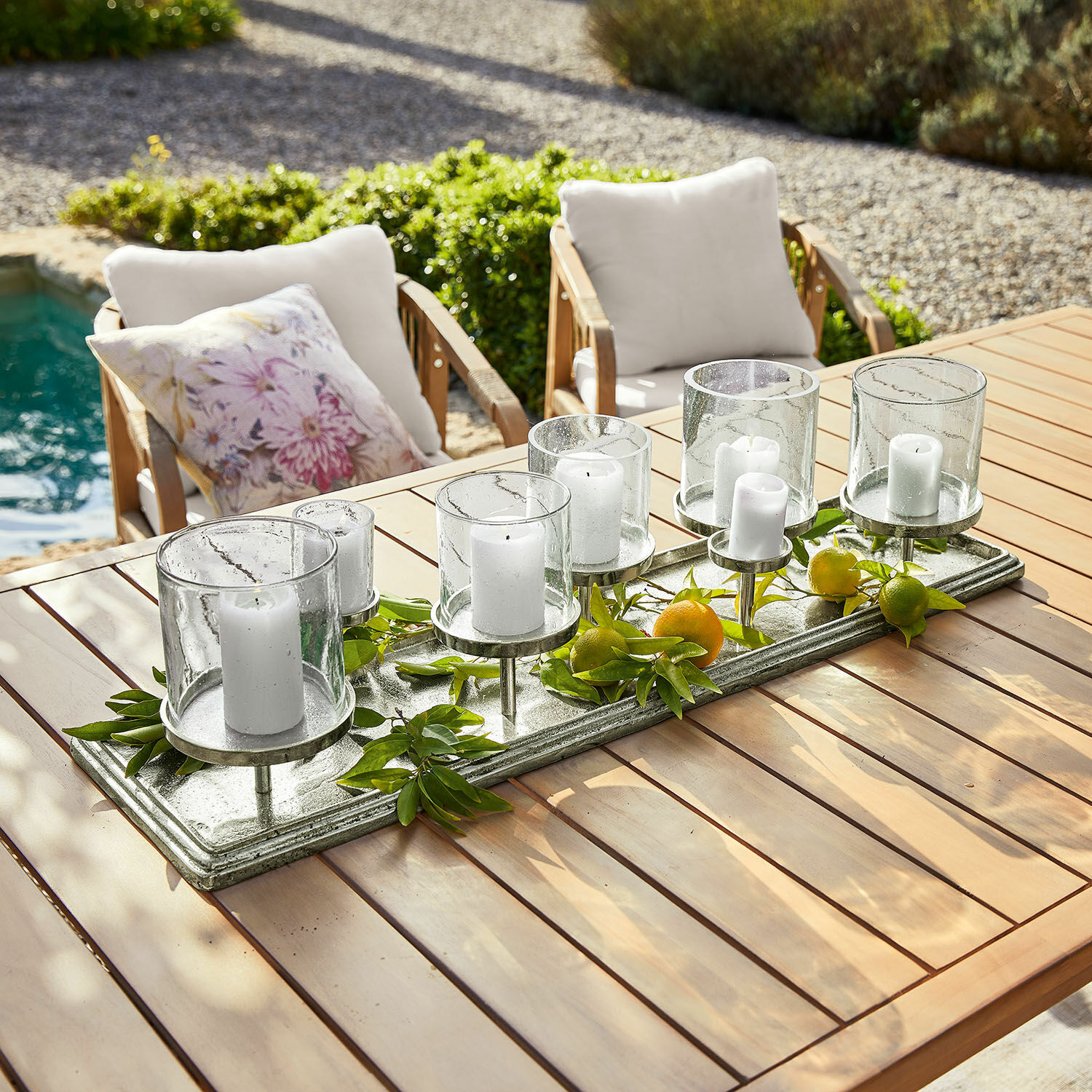 Kaarsenplateau Devonne Decoratieve kandelaar van glas en metaal met witte kaarsen op houten tafel in tuin