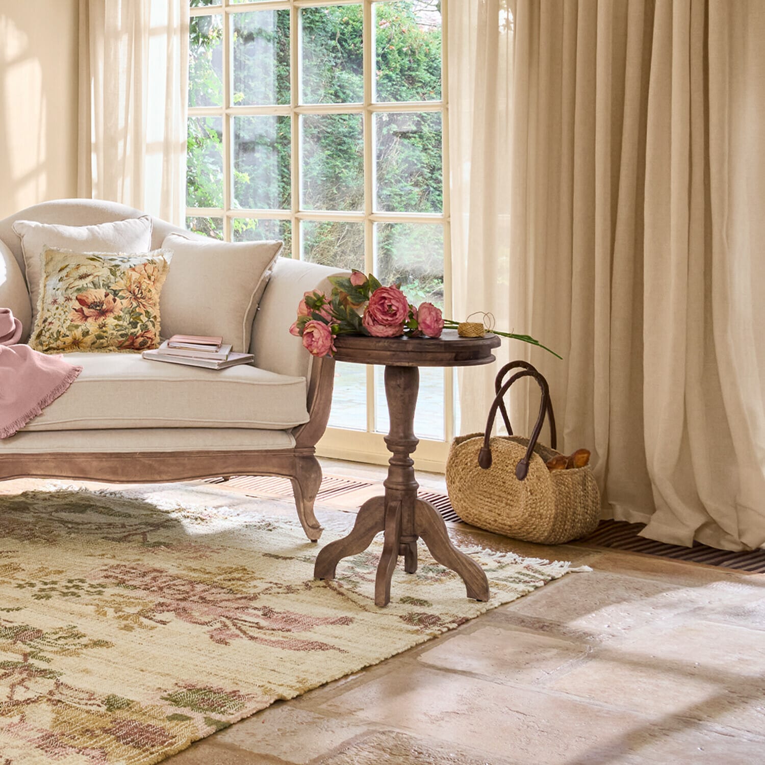 Gezellige woonkamer met beige bank, houten bijzettafel en bloemen op een vloerkleed met bloemenpatroon