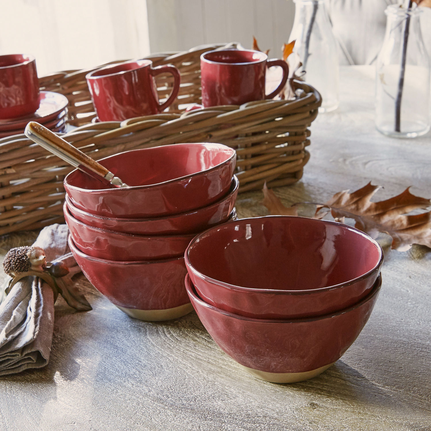 Rode keramische kommen met natuurlijke beige bodem op houten tafel met herfstdecoratie