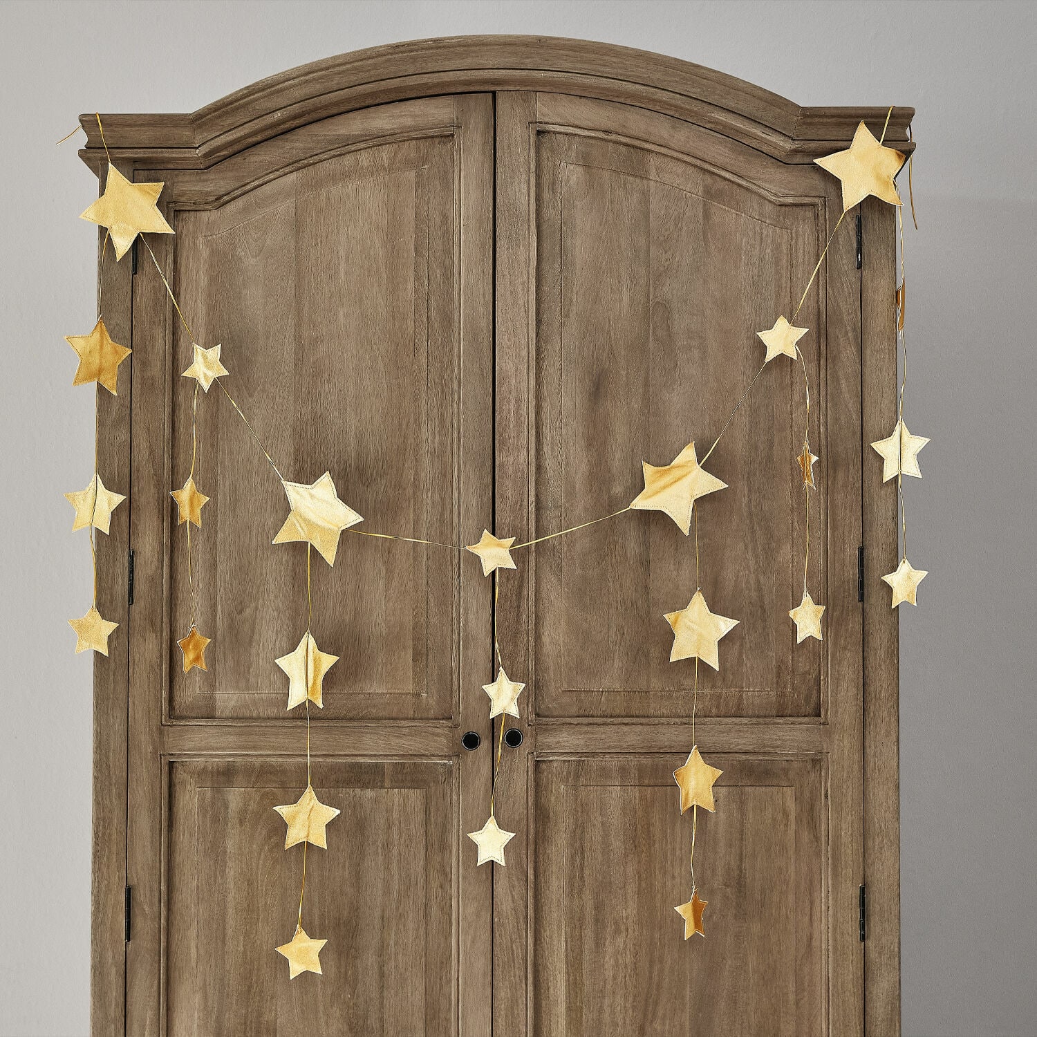 Guirlande Étoilin Gouden sterren slinger aan houten kast, feestelijke woondecoratie voor kerst