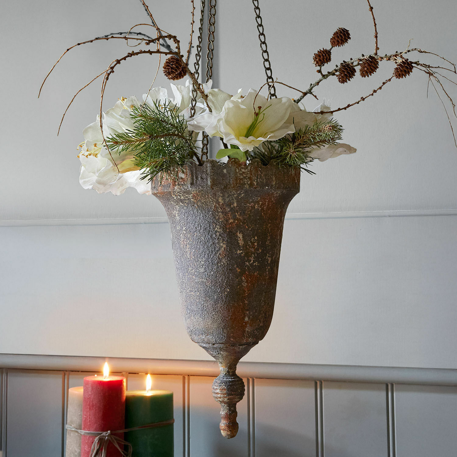 Hangende metalen bloempot in vintage stijl met witte bloemen en dennen takken, interieurdecoratie