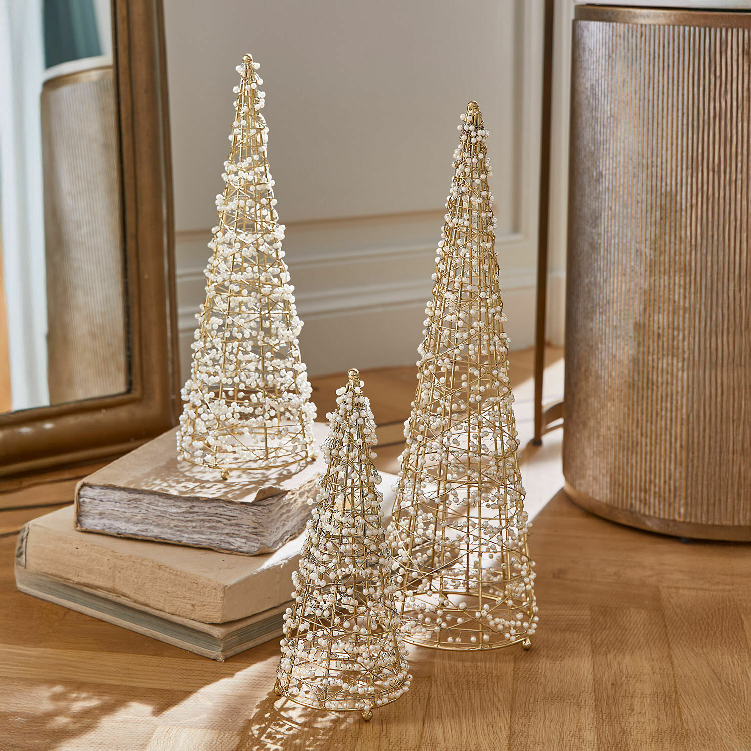 Set van drie decoratieve gouden draadkegels met witte parels op een houten tafel