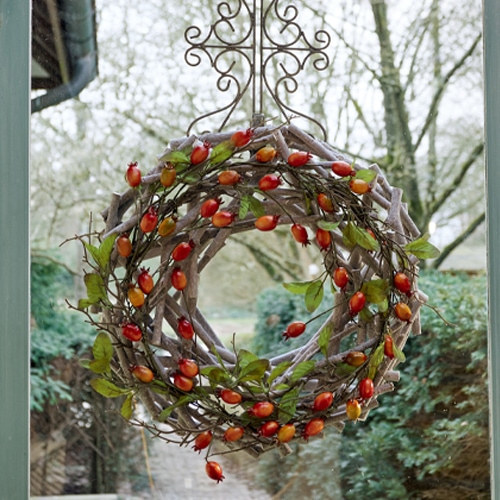 Decoratieve krans van takken met rode bessen, herfstversiering voor de deur