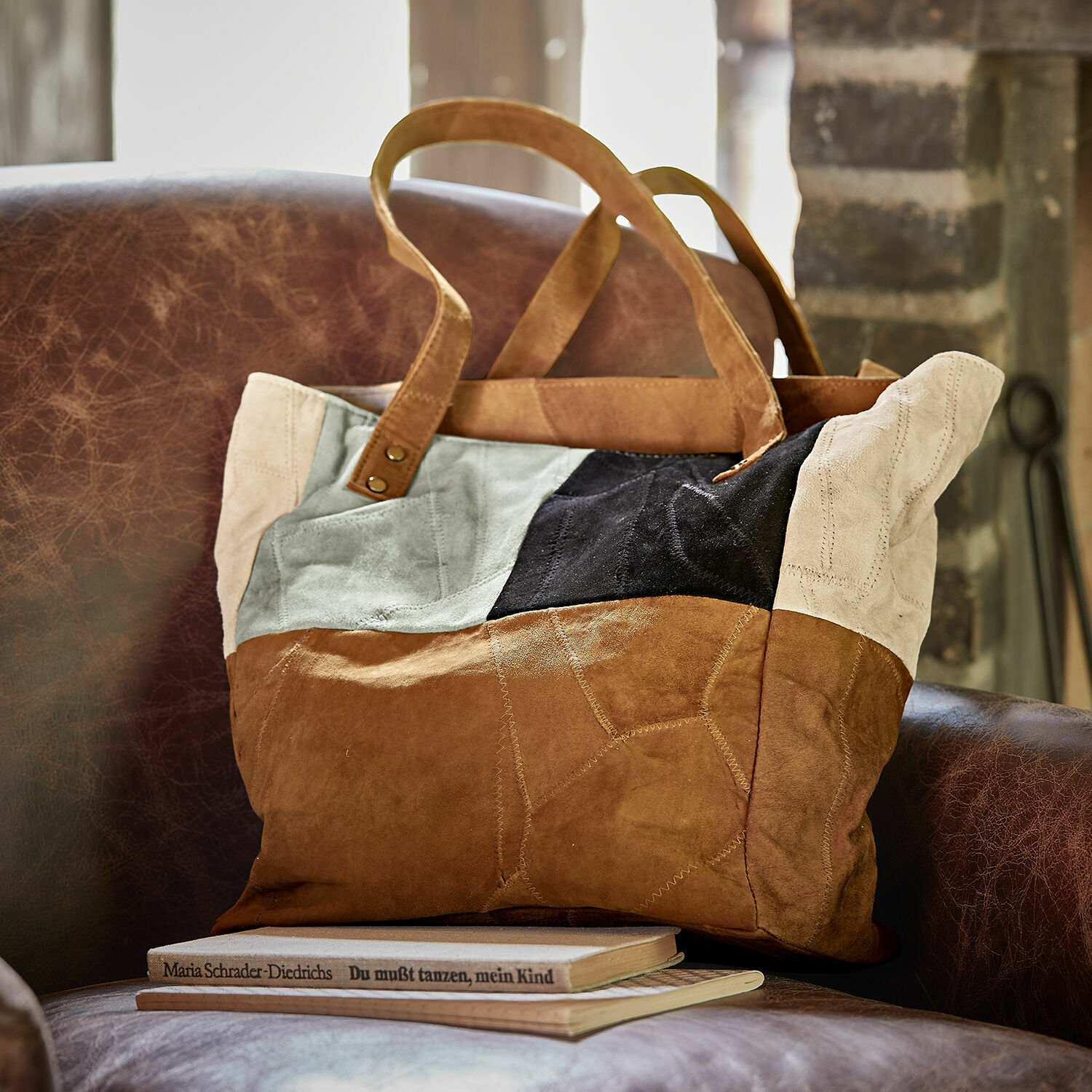 Tas Quinvelle Patchwork tas van suède in bruin, zwart en beige op een bruine leren stoel