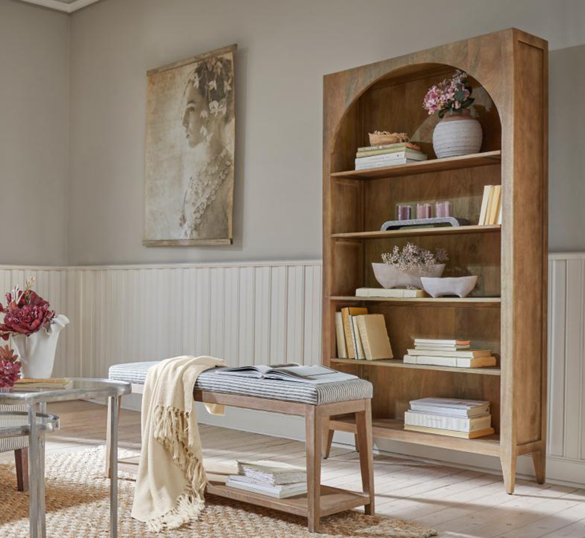 Houten kast met boogvorm, decoraties en boeken in lichte, natuurlijke woonkamer