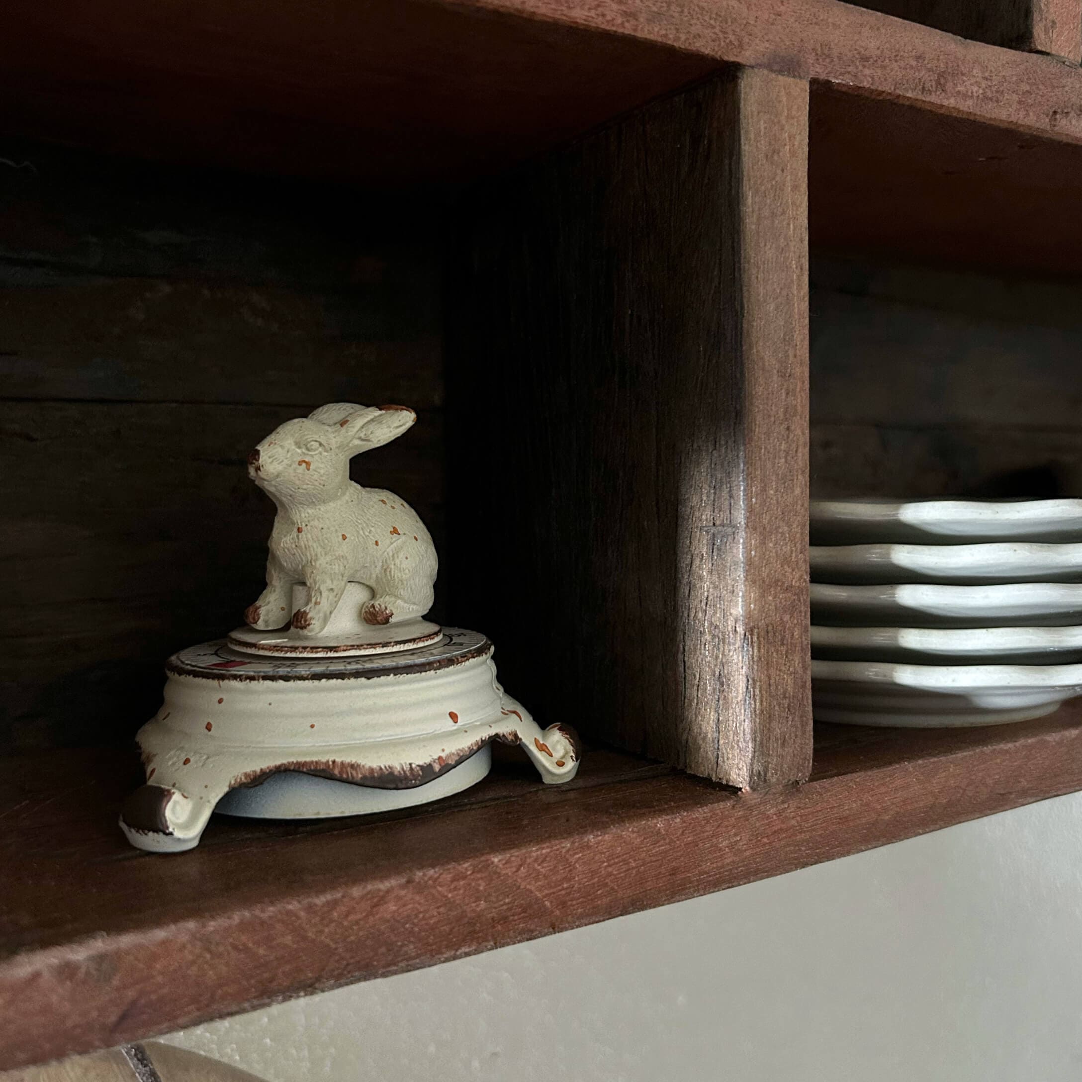 Witte keramische pot met konijnen deksel op houten plank naast borden