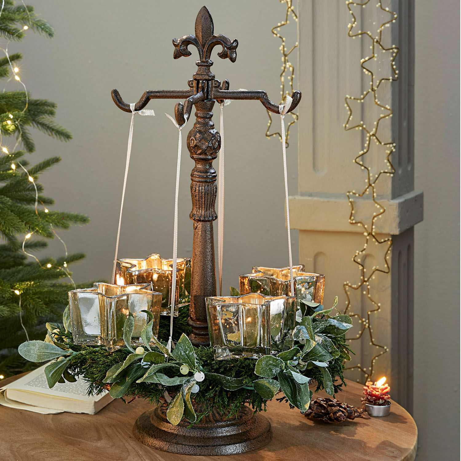 Kranshouder Antwan Metalen standaard met vier glazen theelichthouders en groene decoratieve krans op tafel