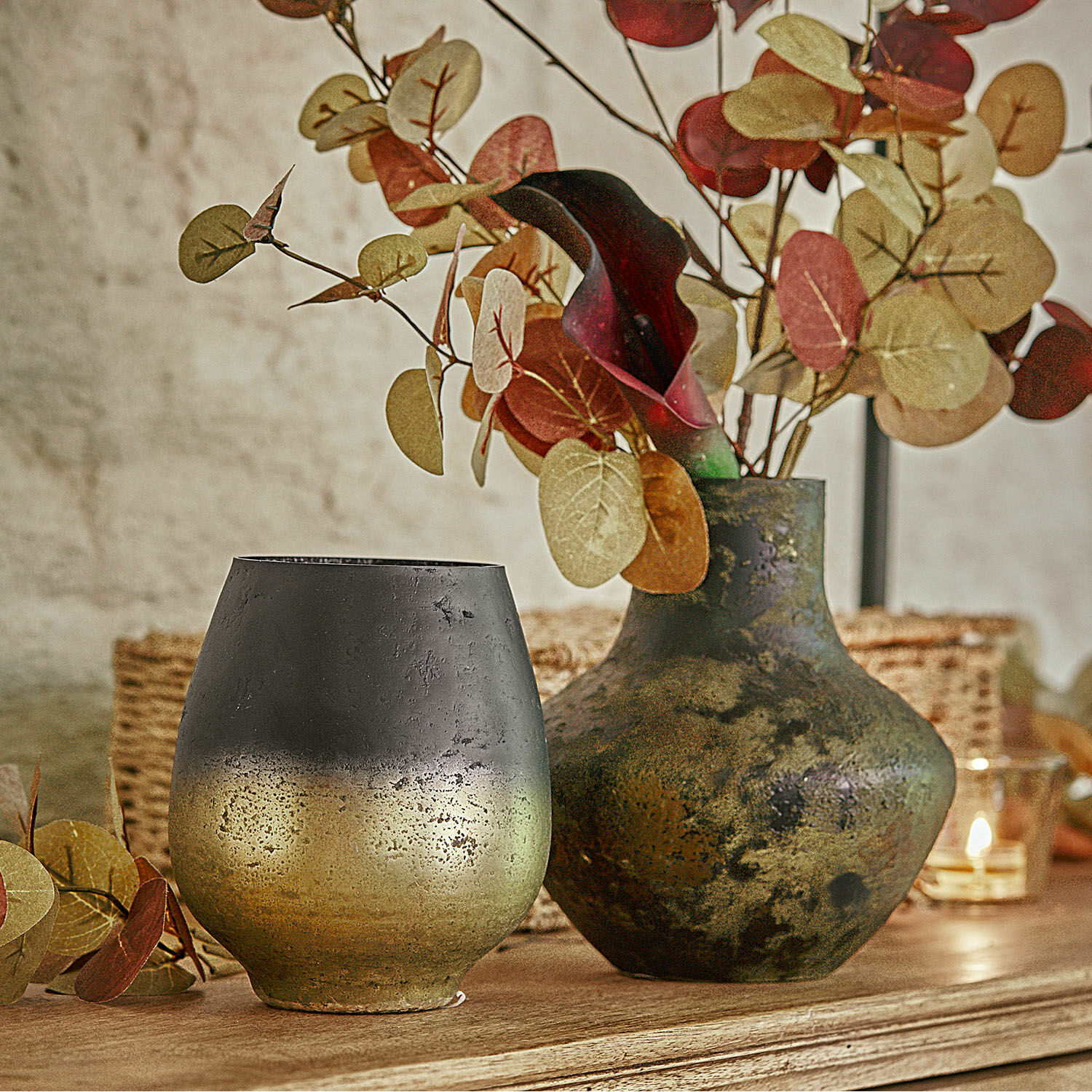 Decoratieve metalen vazen in zwart-goud op houten tafel met herfstbladeren