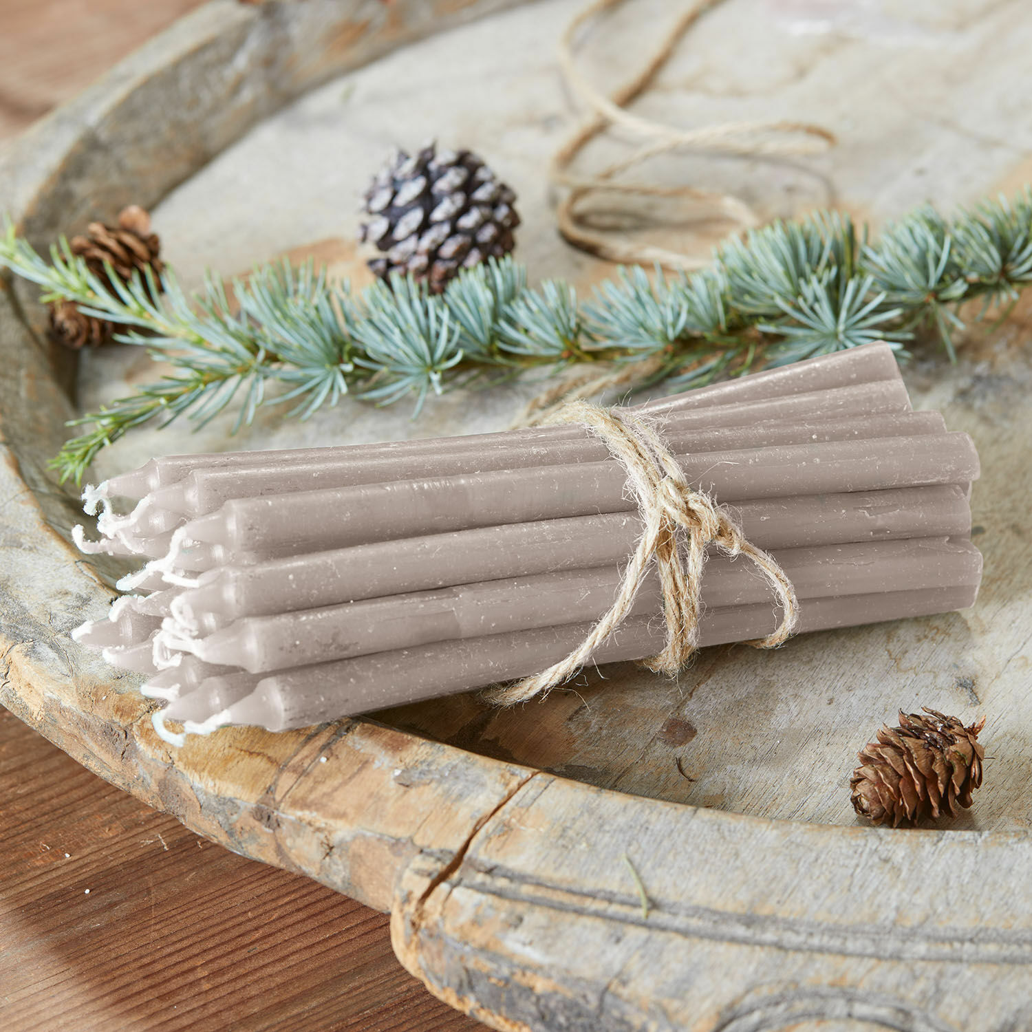 Kaars set van 20 Lysarion Set grijze waskaarsen gebonden met touw op houten dienblad met dennenappels en takken als decoratie