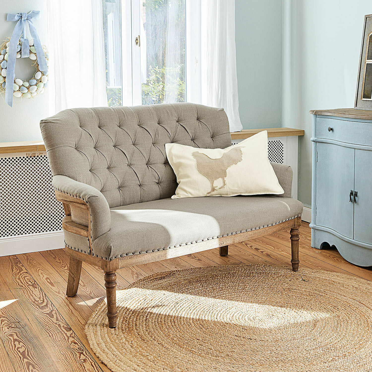 Bank Kingsley Beige gestoffeerde bank met houten frame en decoratieve knopen in lichte woonkamer