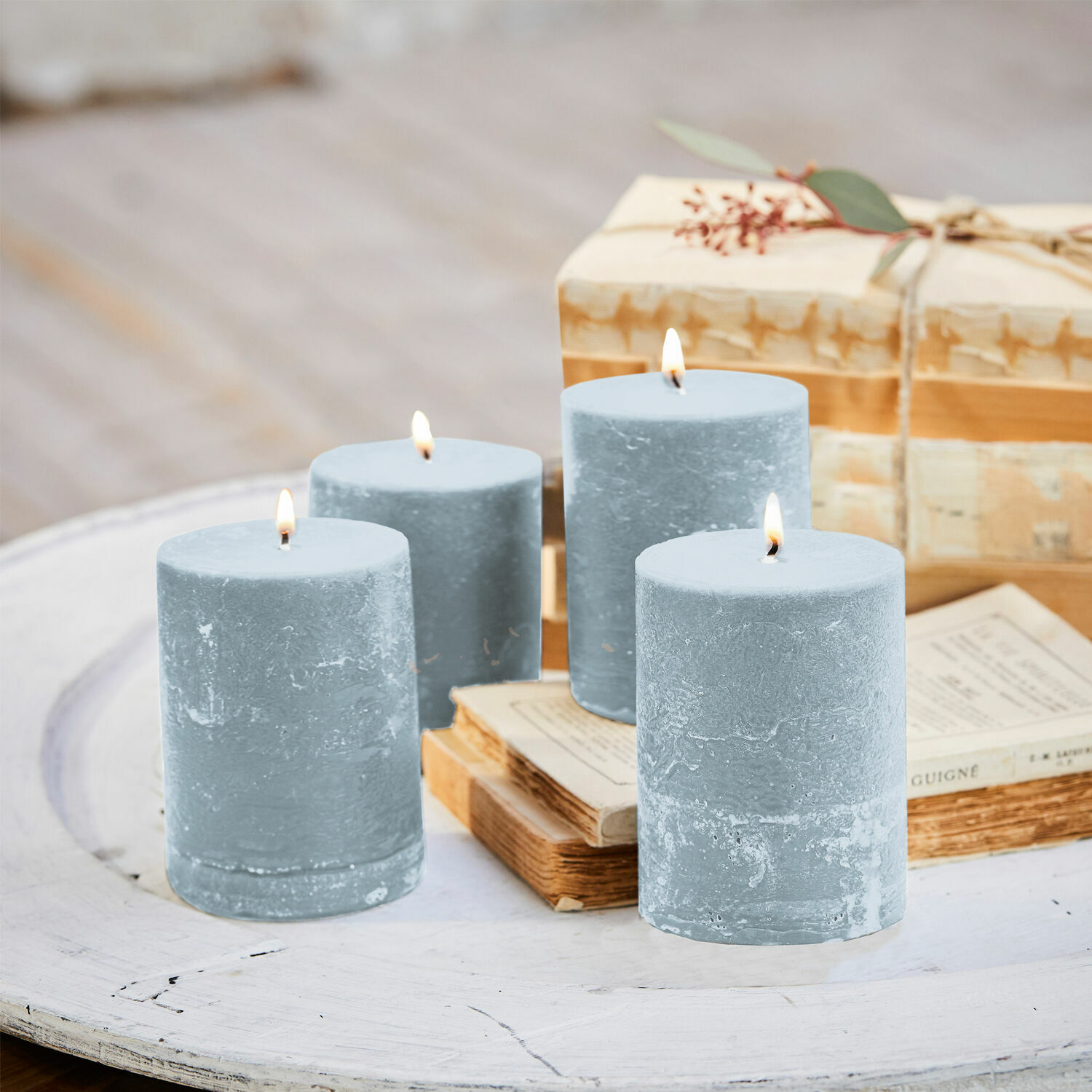 Kaars set van 4 Virrans Set van vier blauwe waskaarsen op witte houten tafel met boeken en cadeau