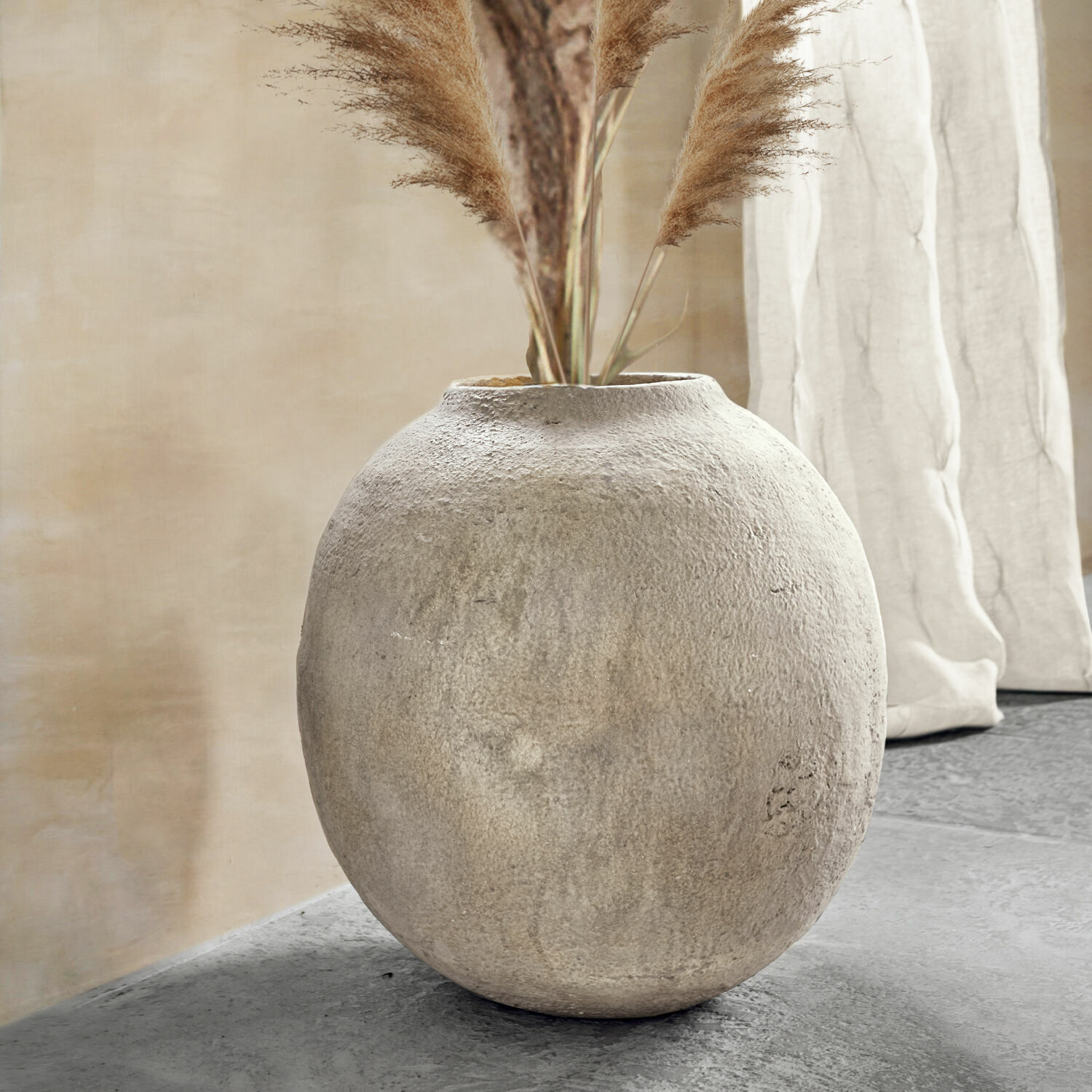 Vaas Samai Ronde grijze betonnen vaas met decoratief pampasgras in een modern interieur