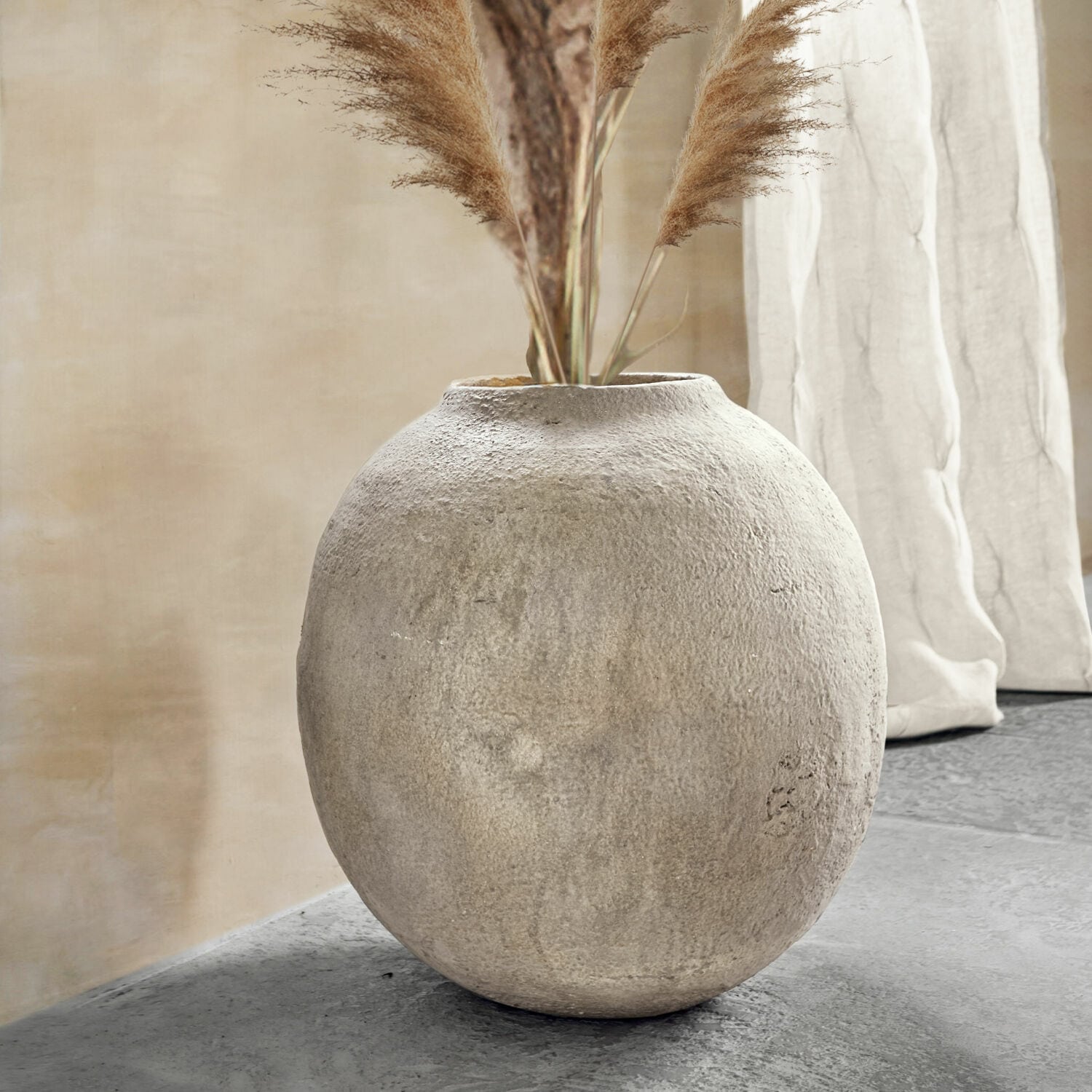 Vaas Samai Ronde grijze betonnen vaas met decoratief pampasgras in een modern interieur