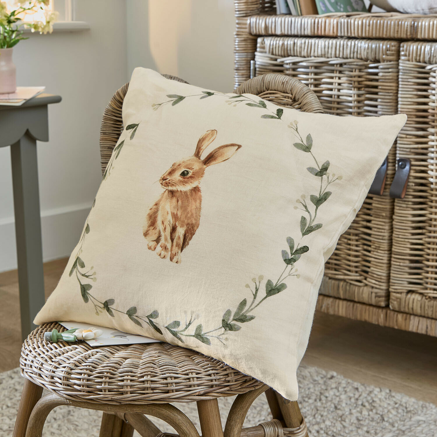 Beige linnen kussen met bruine konijnprint en groene bladeren, sfeervolle woondecoratie