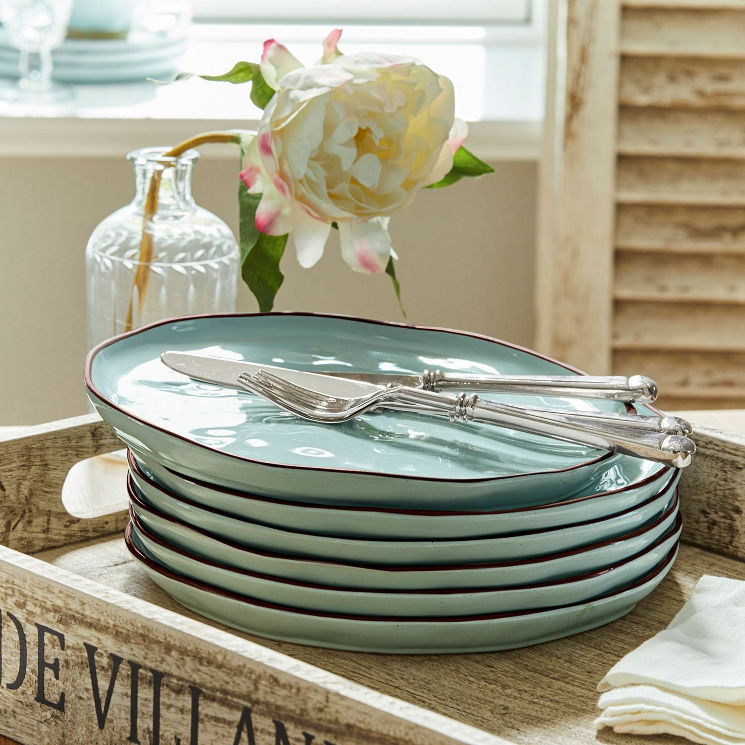 Set van zes keramische borden in muntgroen met bruine rand op een houten dienblad